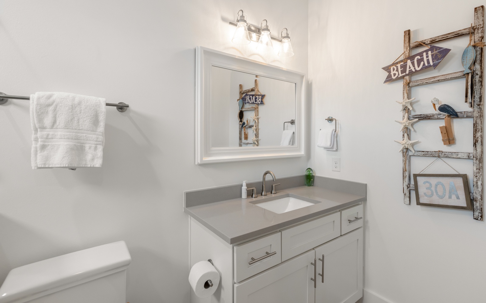 Refresh in your coastal-inspired bathroom with beach decor, clean vanity, and soft towels ready for your stay.