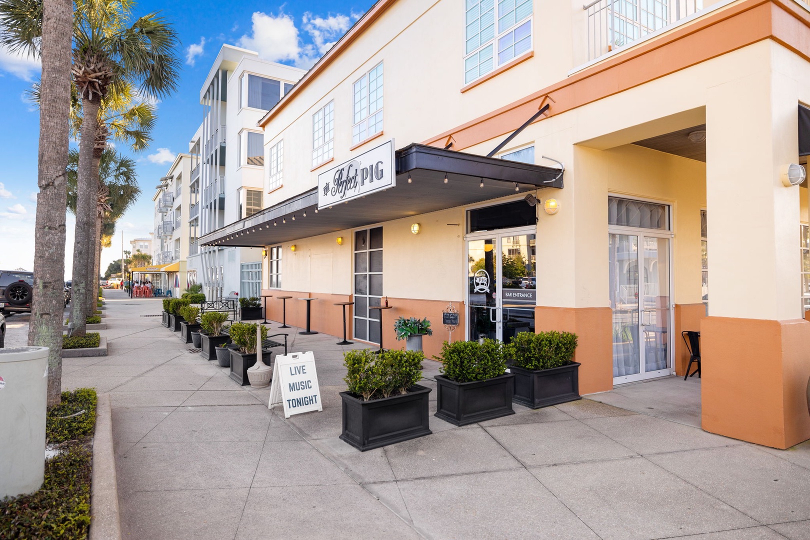 Modern residential buildings and local dining create a vibrant neighborhood atmosphere with palm-lined streets.