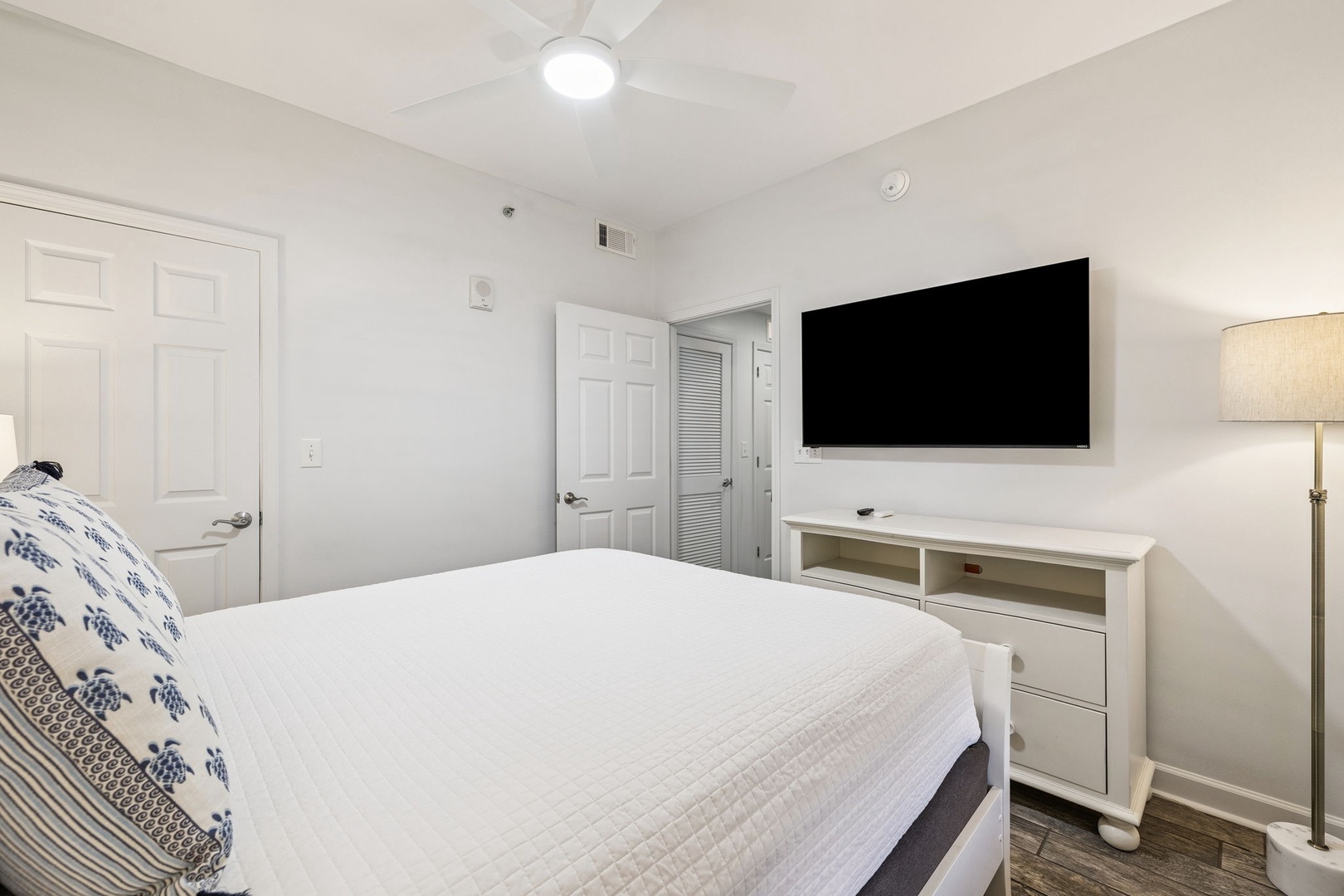 Sink into crisp white linens while enjoying your favorite shows on the large TV in this serene bedroom retreat.