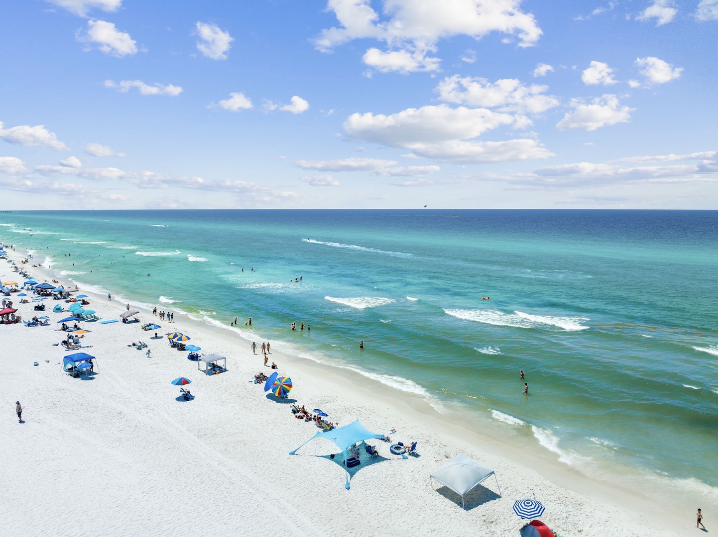 Pristine white sand beach with turquoise waters stretches endlessly along the Gulf Coast, offering world-class swimming and sunbathing opportunities.
