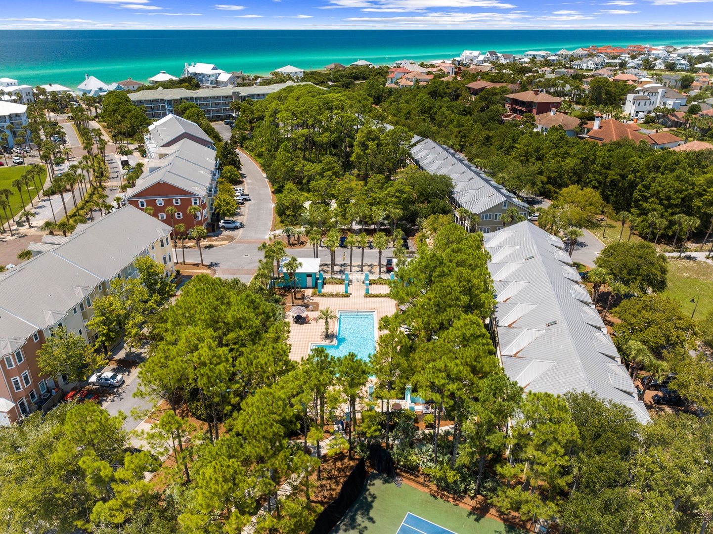 Aerial view of beachside resort property with swimming pool, lush landscaping, and pristine emerald waters just steps away.