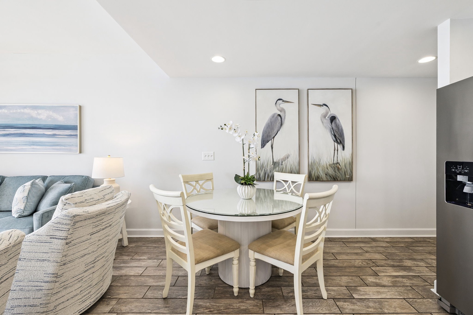 Step into your serene dining space where coastal artwork and soft blues create the perfect atmosphere for memorable meals together.