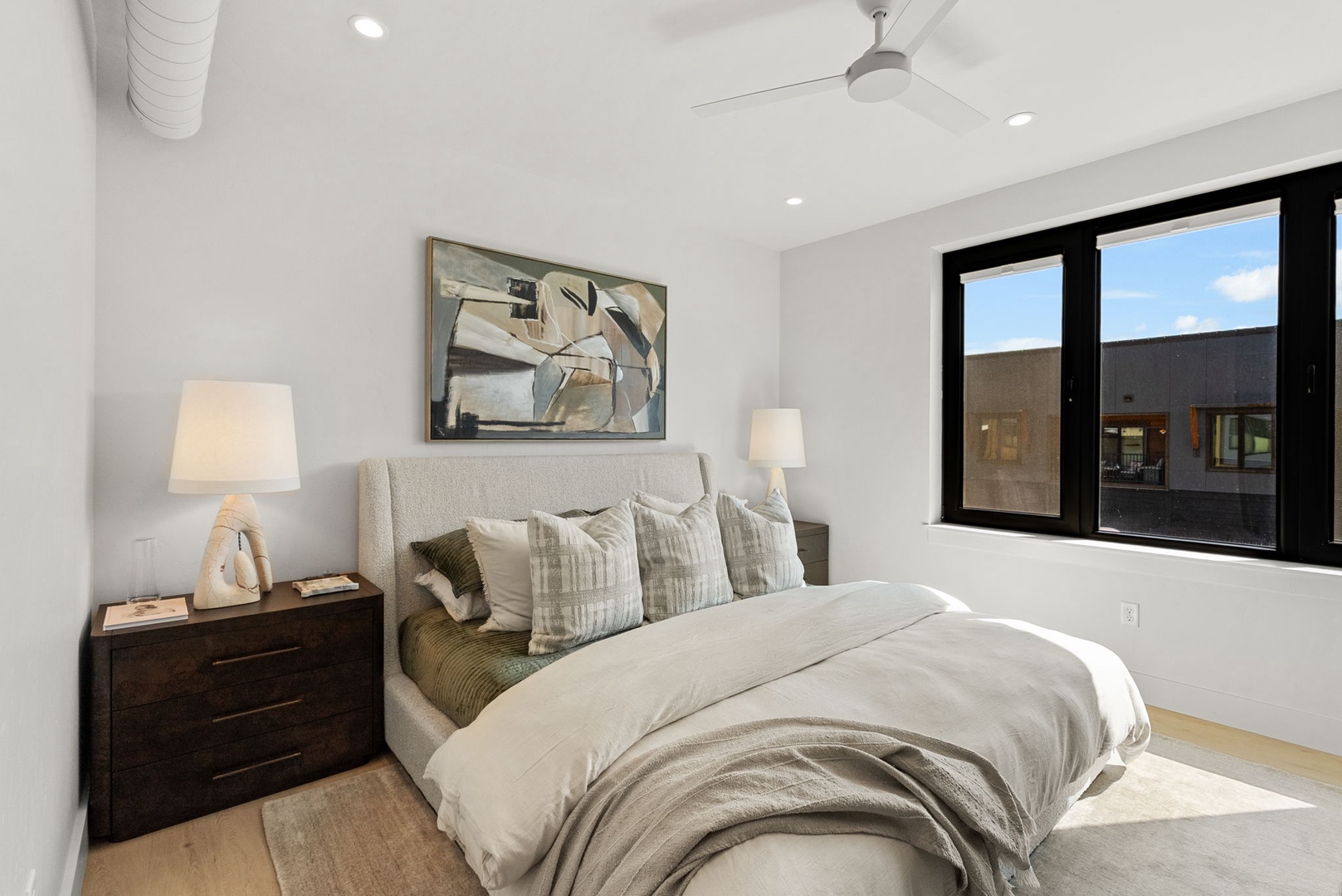 Sink into plush bedding and wake to soft natural light streaming through sleek black-framed windows. Your peaceful bedroom retreat features modern touches and clean lines for ultimate relaxation.