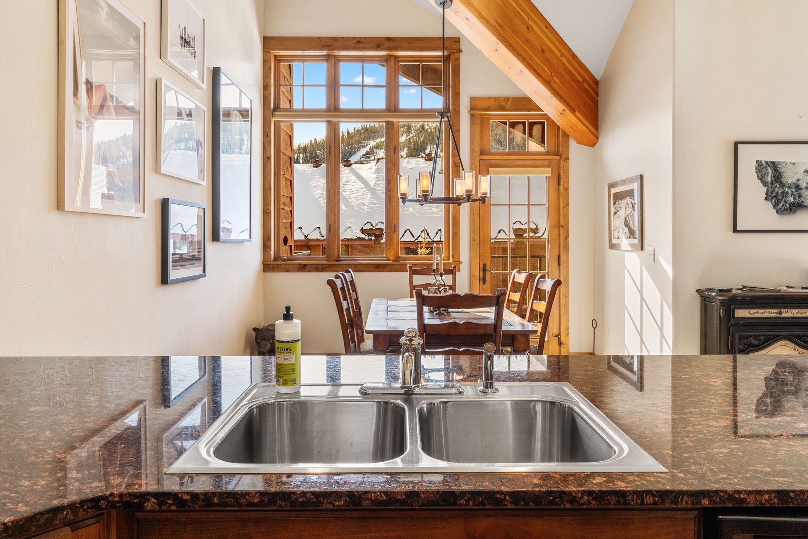Your fully equipped kitchen opens to a cozy dining area with warm wood accents and mountain views through charming windows.