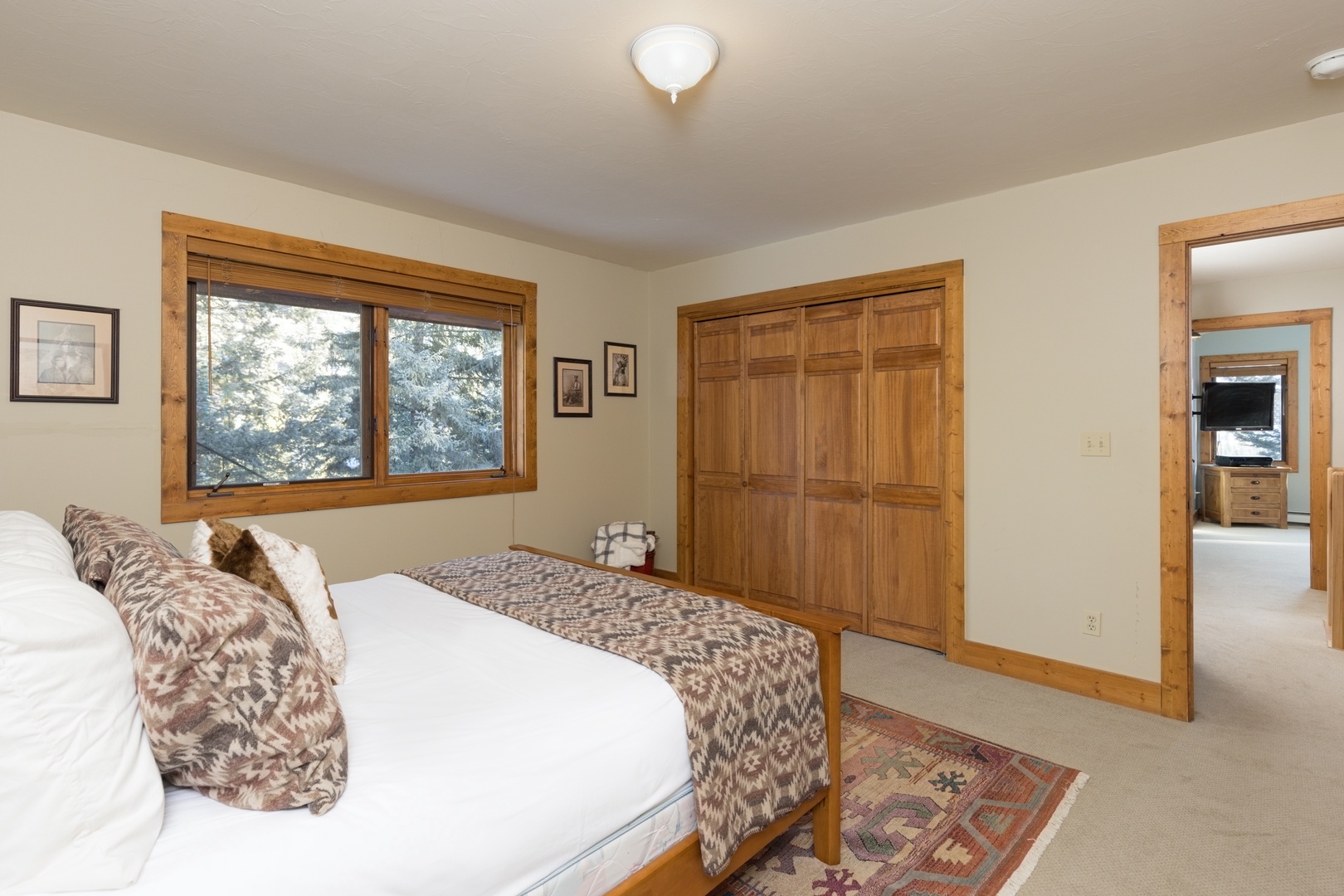 Sink into crisp linens in your peaceful bedroom, where natural light streams through windows and warm wood accents create a cozy mountain retreat.
