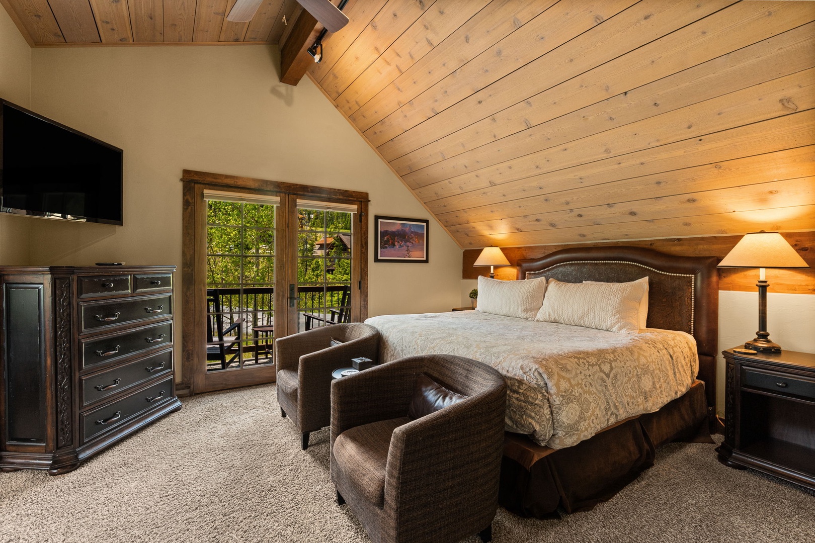 Sink into your plush king bed beneath warm wood ceilings, with French doors opening to a private balcony surrounded by greenery.