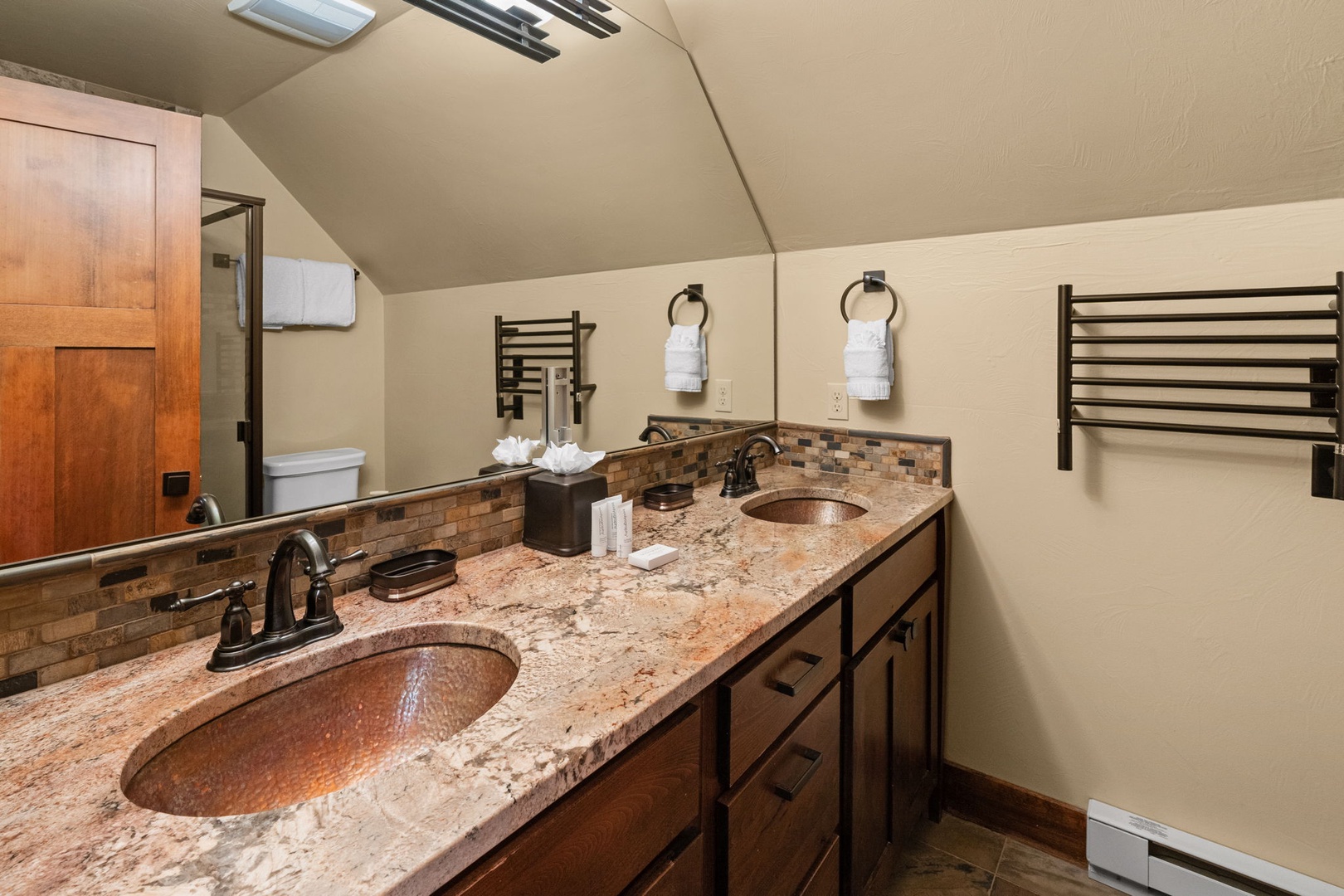 Refresh in your dual-sink bathroom with elegant granite countertops, copper basin sinks, and warming towel racks to wrap yourself in comfort after every shower.