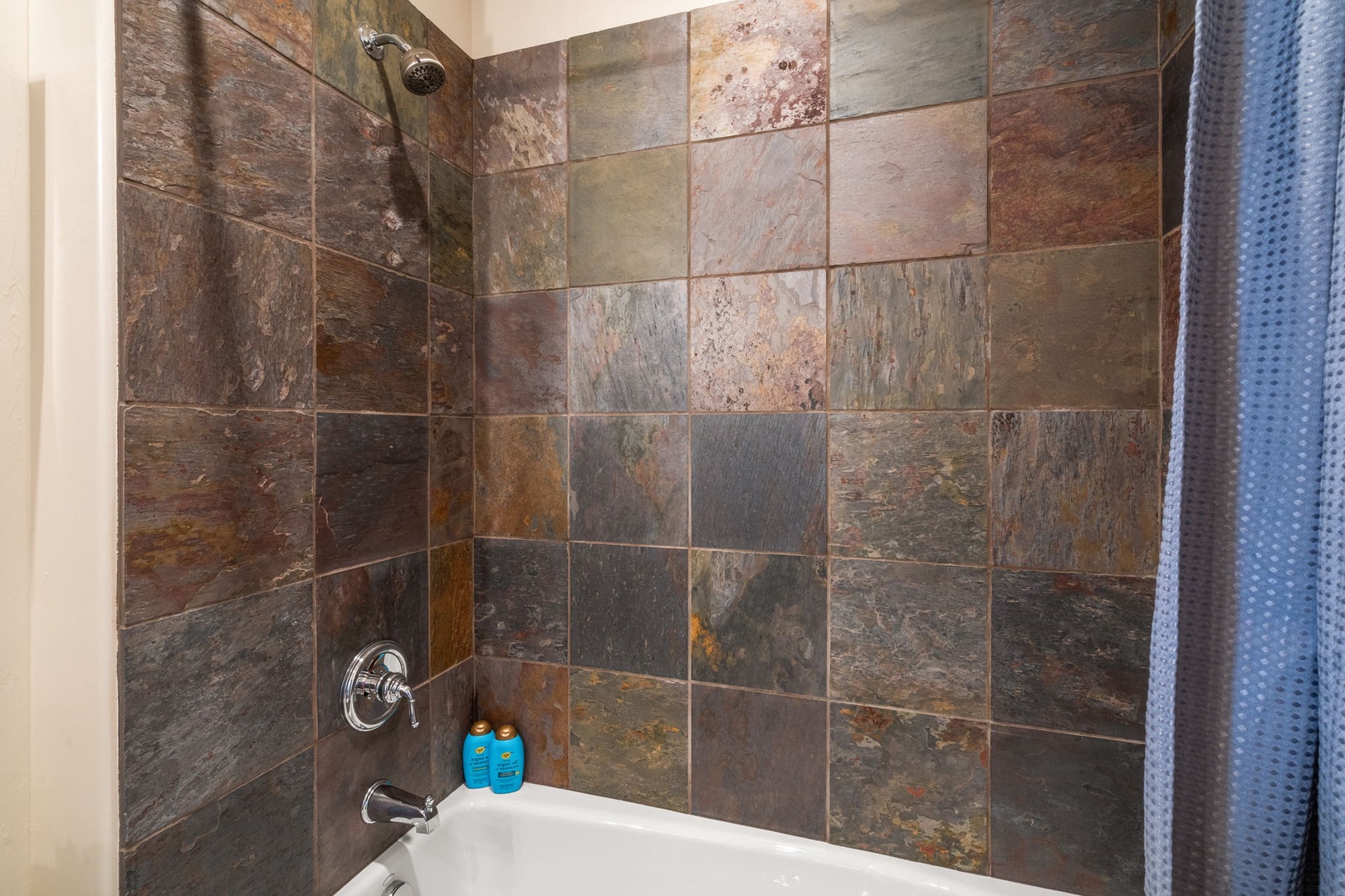 Unwind in your elegant bathroom featuring stunning natural stone tiles and a relaxing tub-shower combo for refreshing moments.
