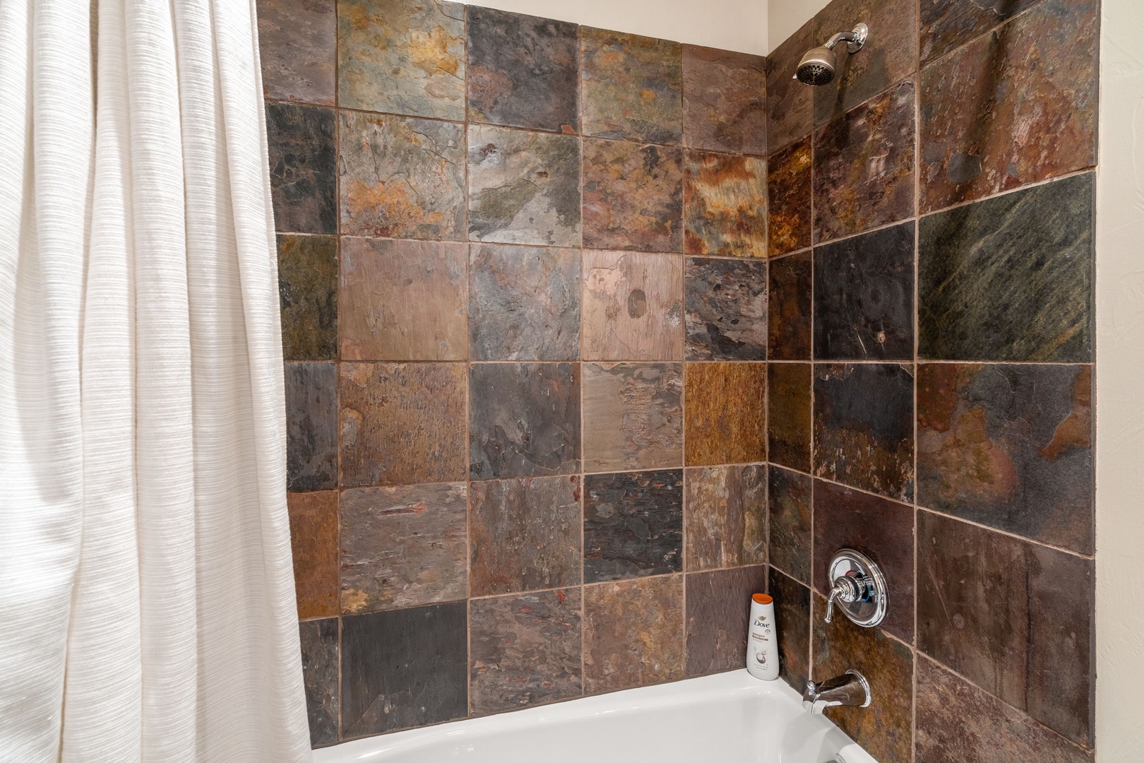 Unwind in your slate-tiled sanctuary with a deep soaking tub and rainfall shower. The natural stone creates a spa-like retreat for ultimate relaxation.