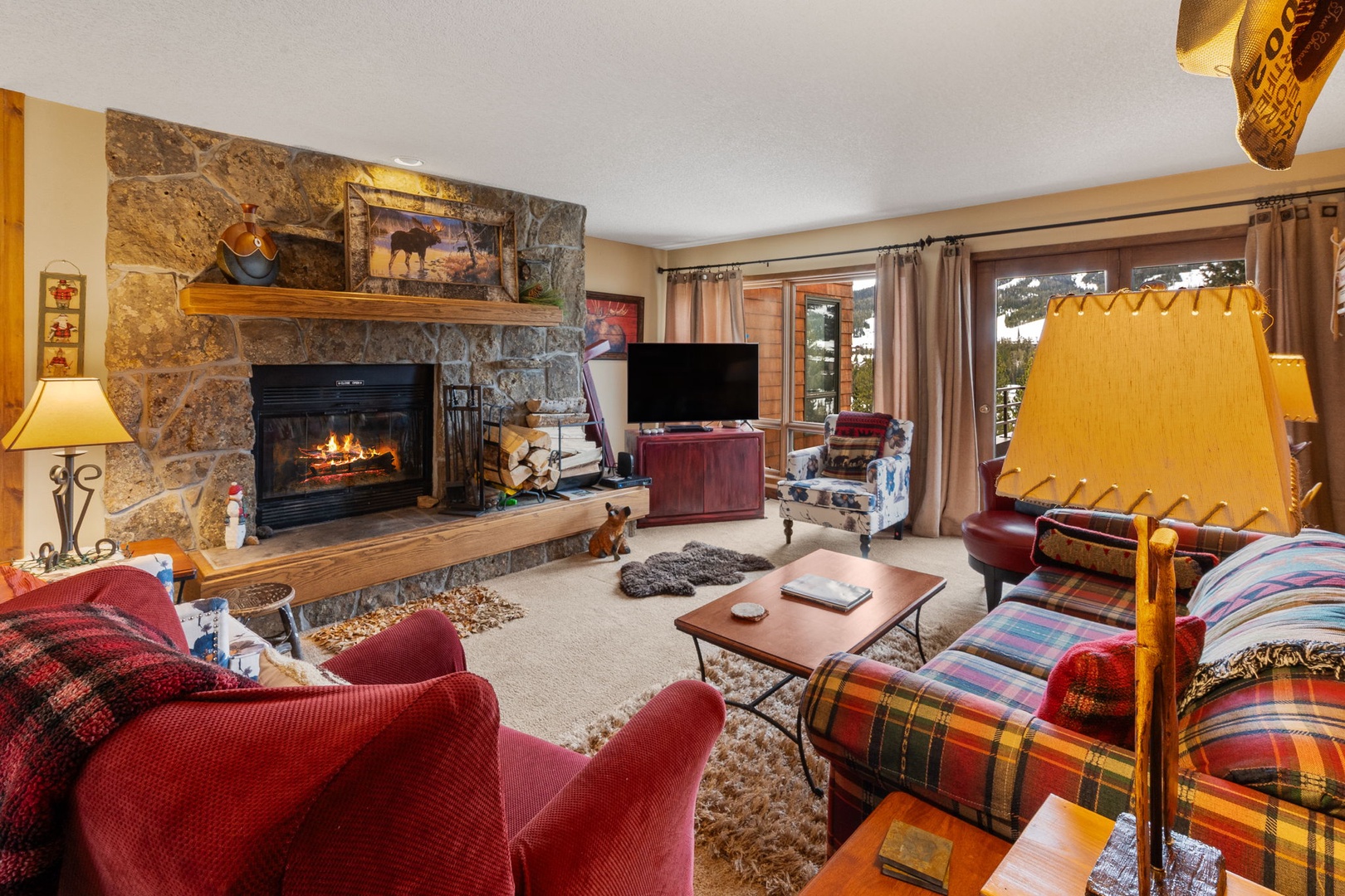 Cozy up by your crackling stone fireplace with plaid furnishings and mountain views creating the perfect alpine retreat.