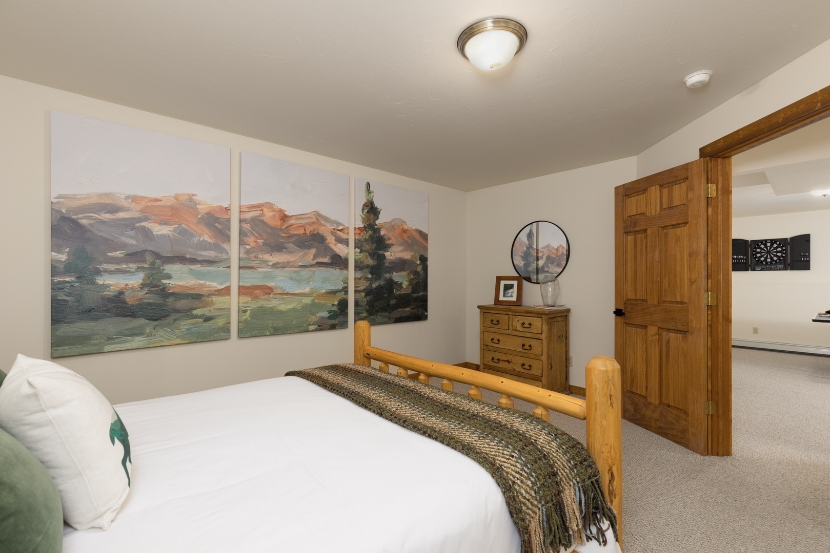 Drift off in your cozy bedroom featuring rustic wood furnishings and stunning mountain landscape art above your comfortable bed.