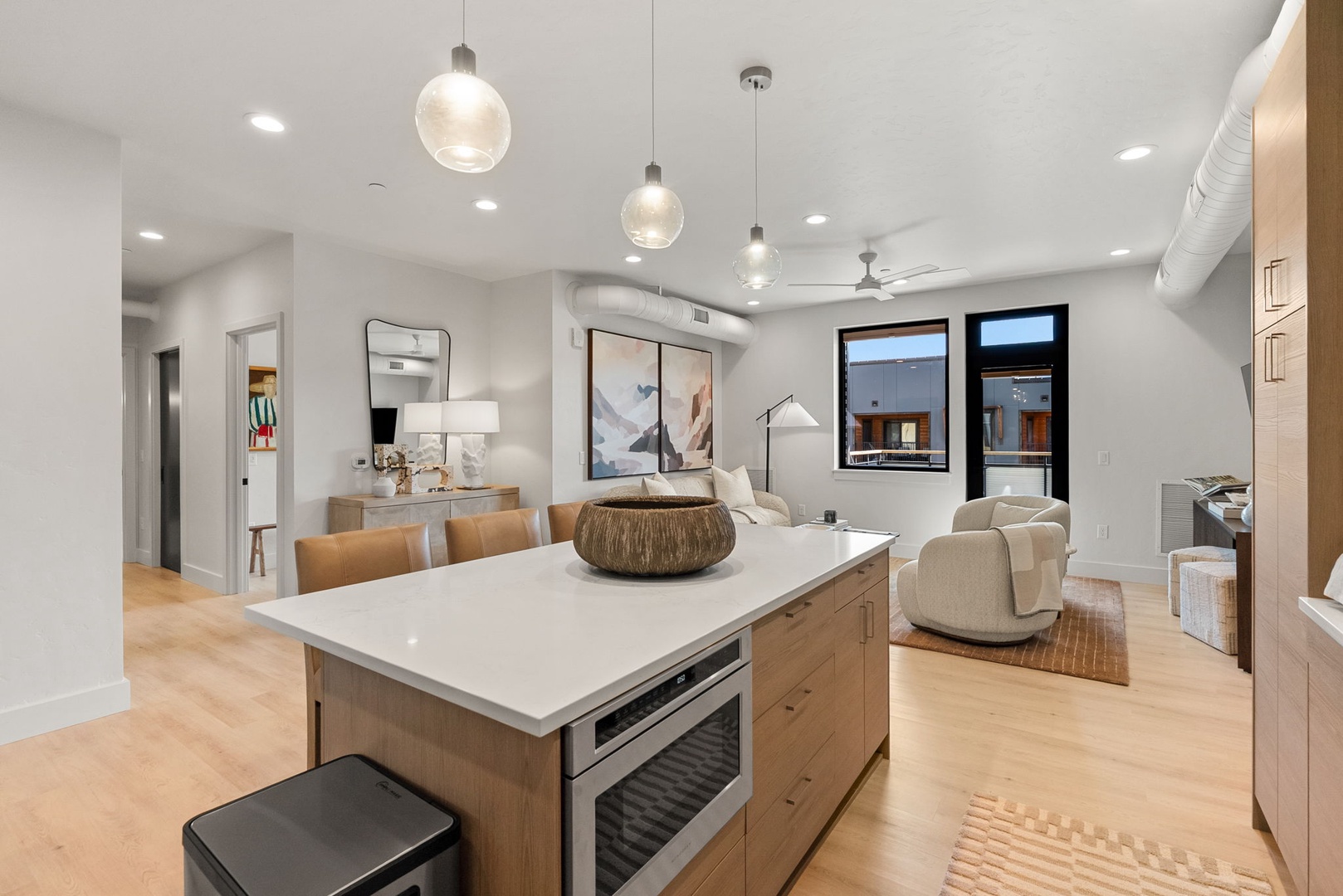 Step into your modern haven where natural light pours over warm wood tones and sleek surfaces. The open kitchen island invites you to gather, cook, and relax while staying connected to your living space.
