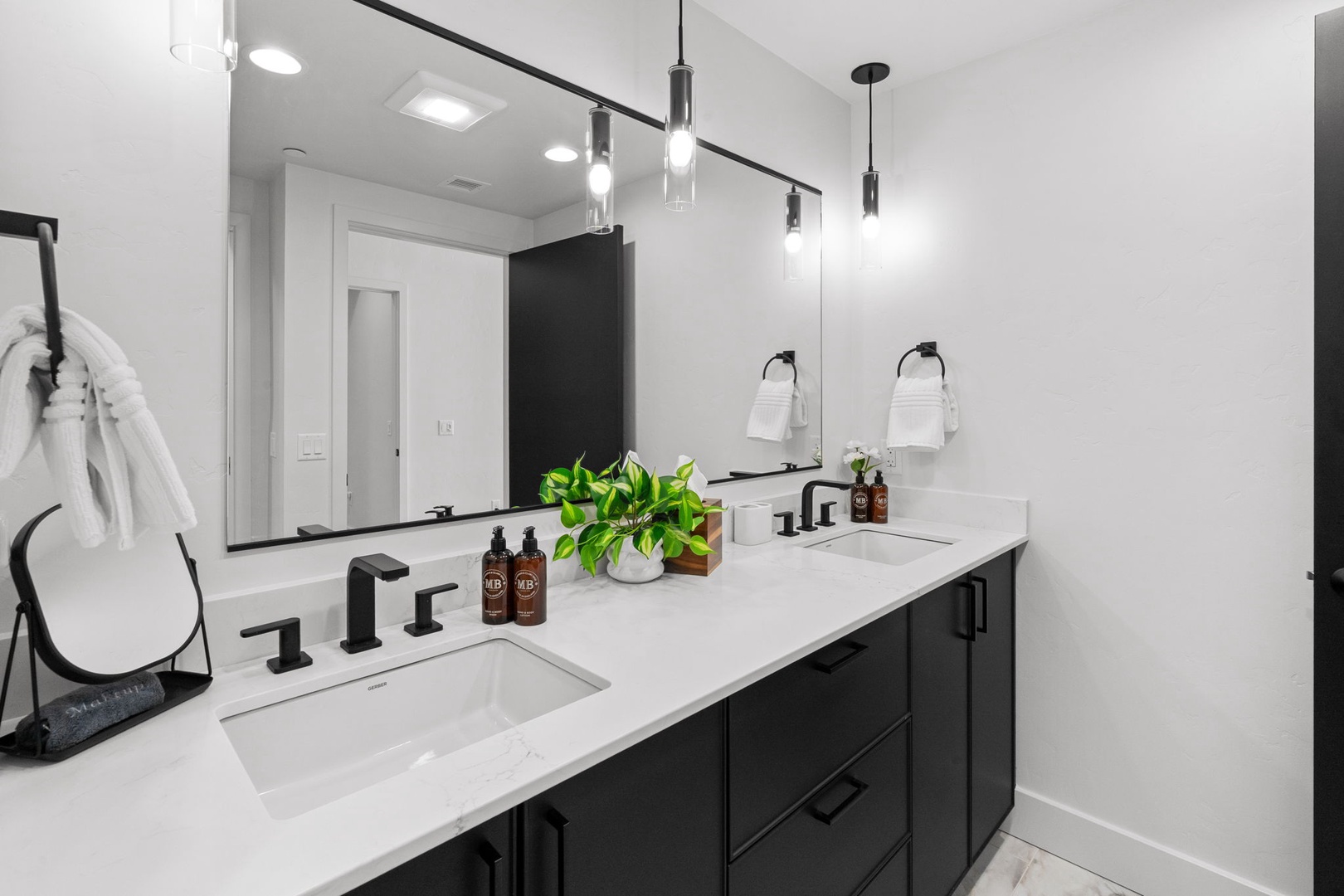 Step into your sleek bathroom featuring dual vanities, modern pendant lighting, and spa-like amenities for your morning routine.