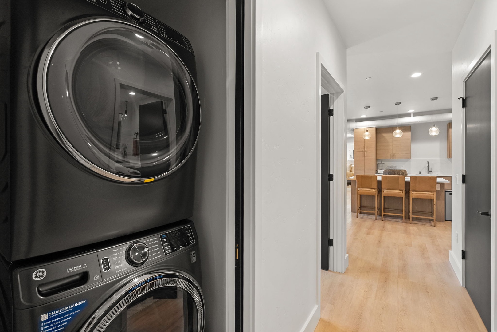 A stacked washer and dryer tucked neatly into your hallway keeps laundry convenient, while the bright modern kitchen beckons just steps away.