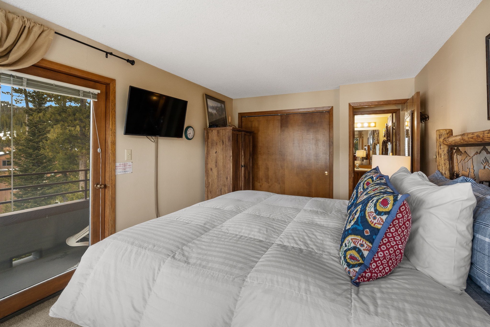 Drift off peacefully in your cozy bedroom featuring a plush bed, warm wood accents, and TV for relaxation.