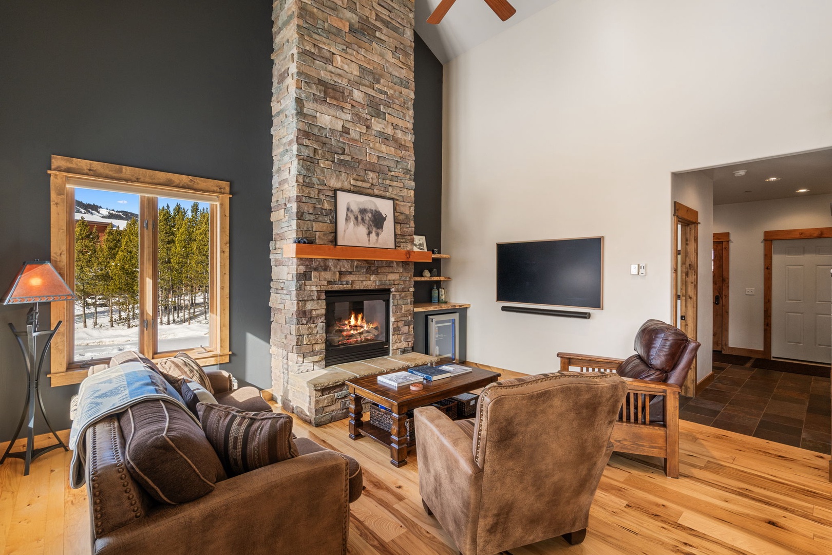 Cozy up by your crackling stone fireplace with mountain views through expansive windows, creating the perfect alpine retreat atmosphere.