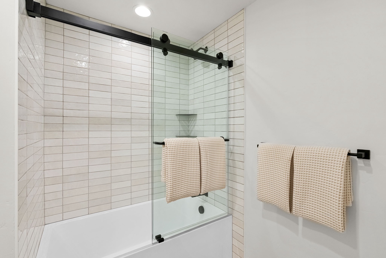 Soak away stress in your sleek tub-shower combo, where crisp white subway tiles and modern glass doors create a fresh, spa-like retreat.