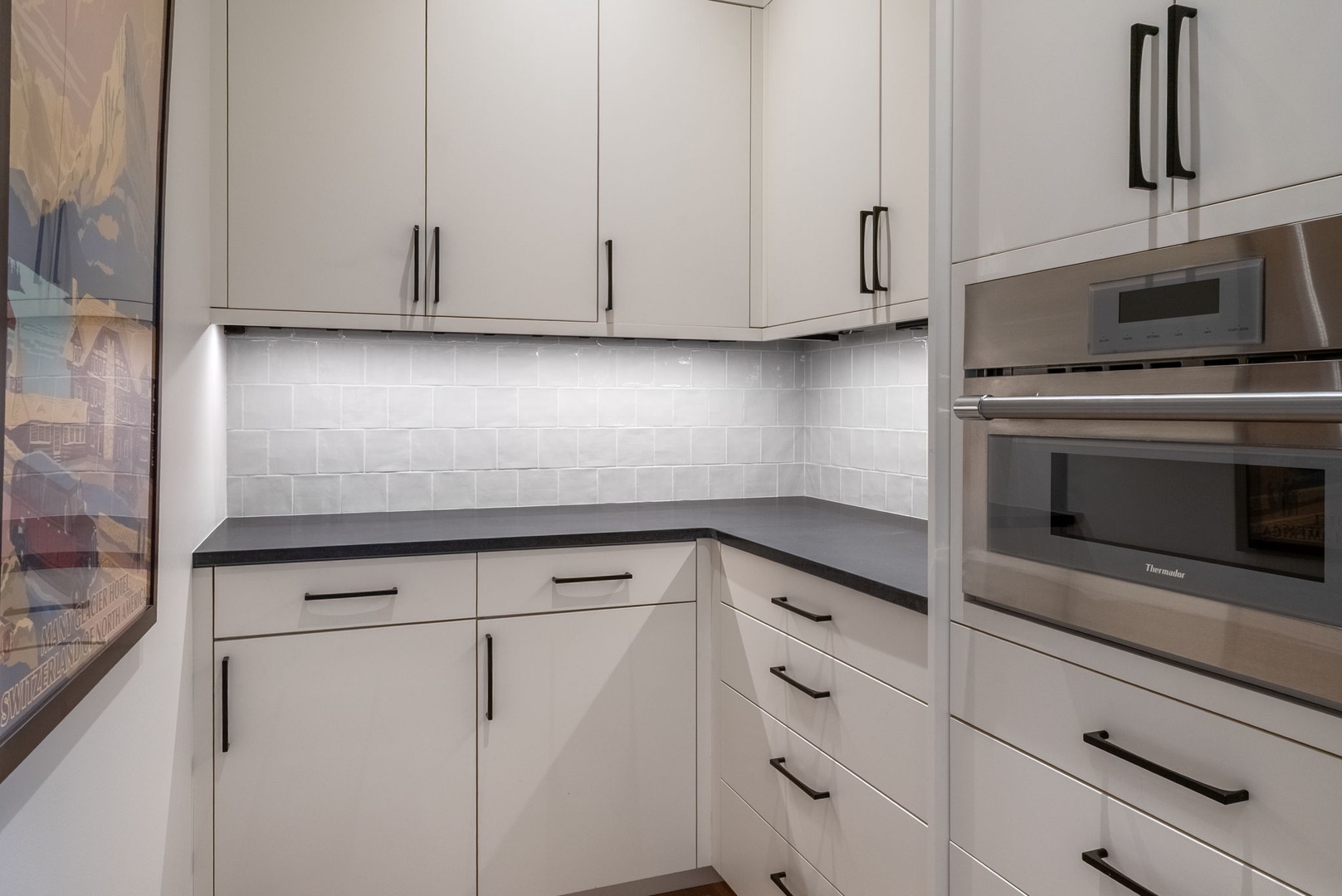 Whip up your favorite meals in this sleek modern kitchen, featuring pristine white cabinetry, granite counters, and built-in appliances.