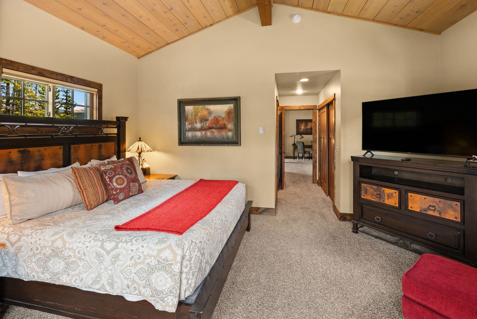 Unwind in your spacious bedroom with vaulted wood ceilings, a plush bed with cozy linens, and a large flat-screen TV for your relaxation and entertainment.