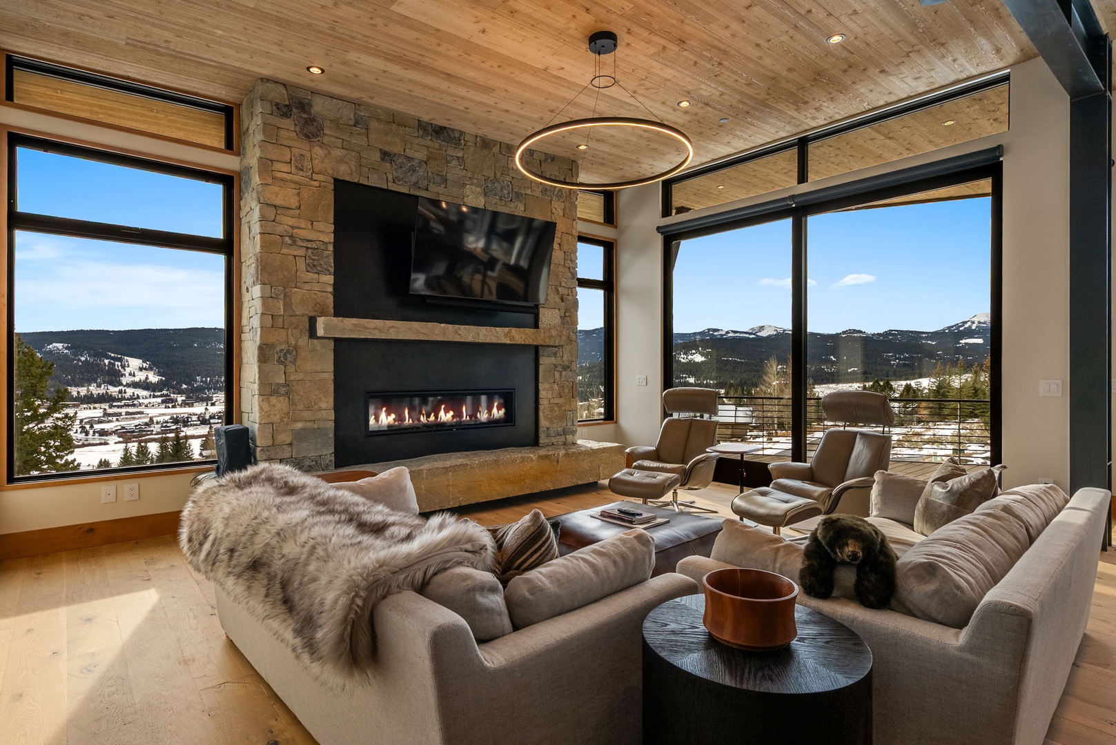 Cozy up by your crackling fireplace while soaking in breathtaking mountain views through floor-to-ceiling windows in this luxurious living space.
