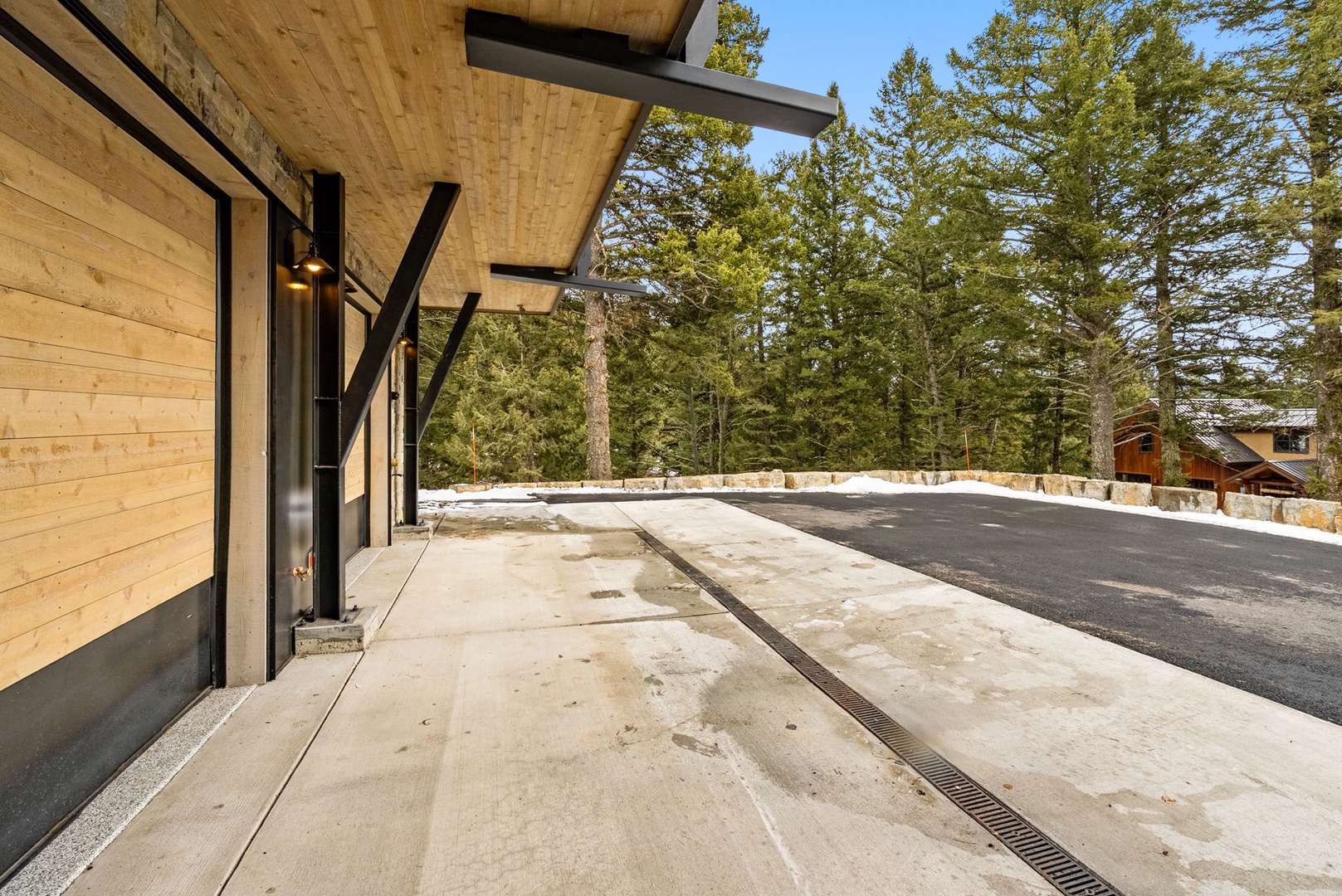 Modern mountain retreat featuring natural wood siding and sleek design, nestled among towering evergreens with convenient paved access.