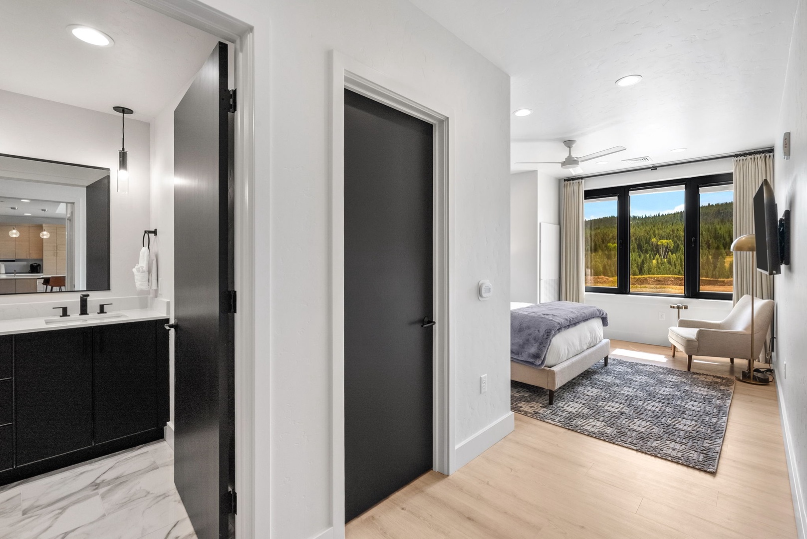 Your modern bedroom opens to sweeping forest views through expansive windows, with a sleek ensuite featuring marble finishes and plenty of natural light.