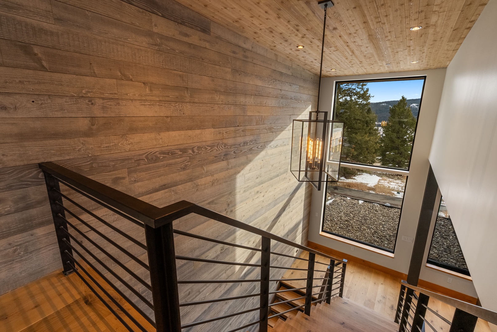 Stunning mountain views frame this modern stairway landing, where warm wood meets sleek design for your peaceful mountain retreat.