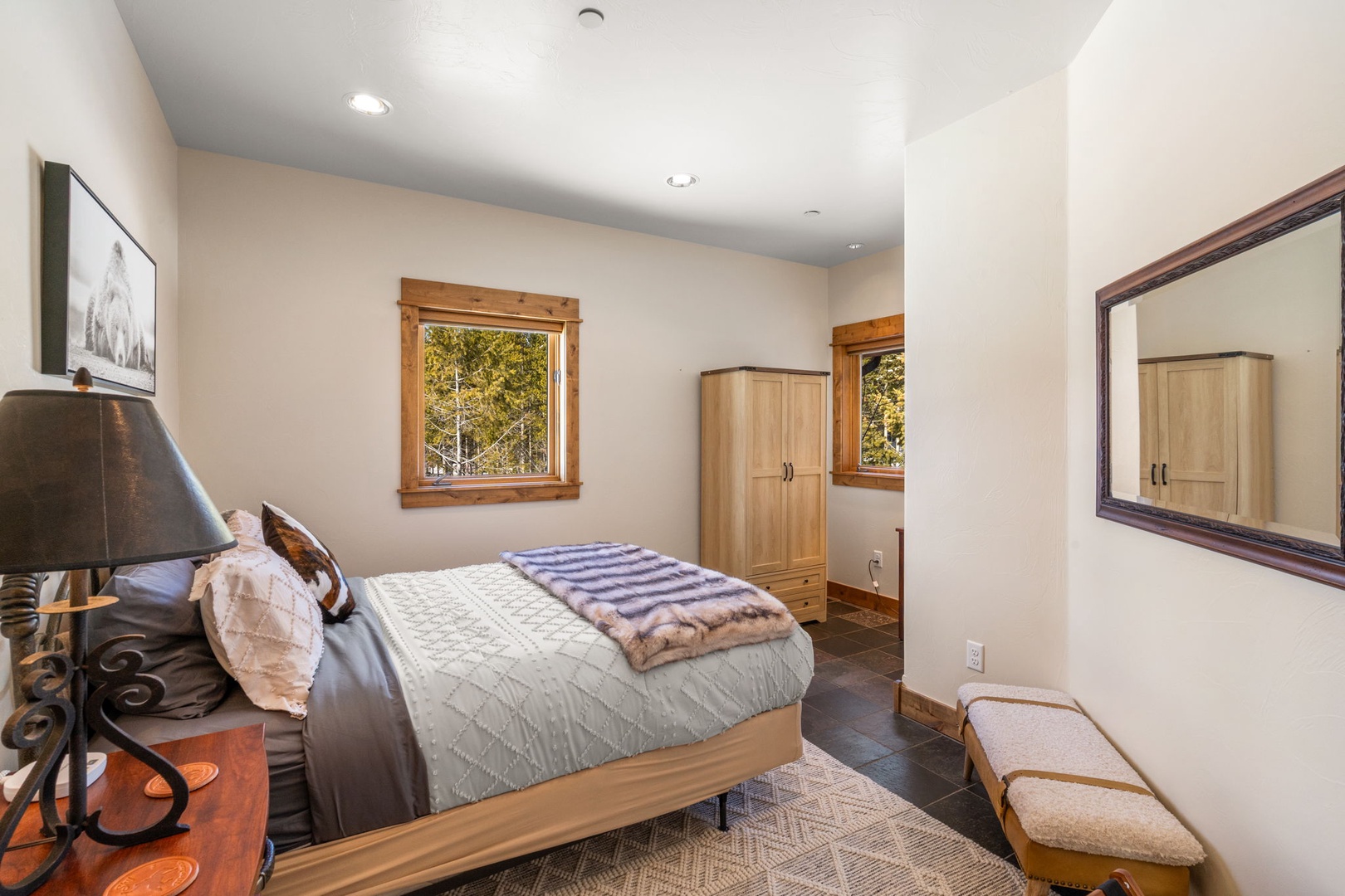 Rest peacefully in your cozy bedroom with warm wood accents, soft linens, and forest views through charming windows.