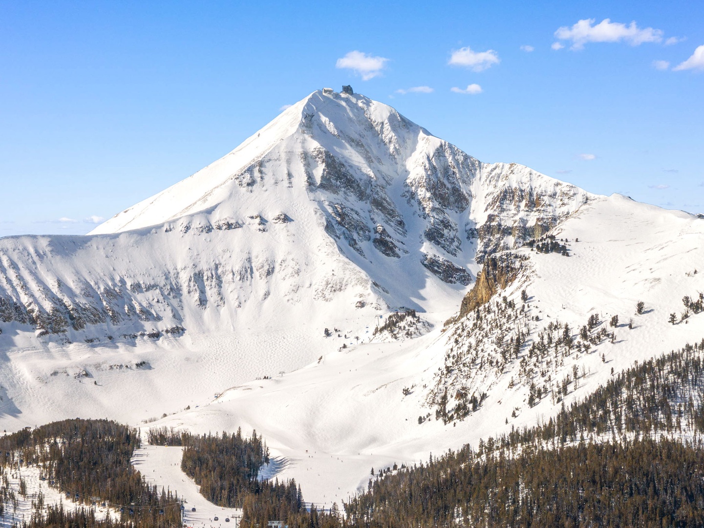 Snow-capped mountain peaks create a dramatic backdrop against brilliant blue skies in this stunning winter landscape.