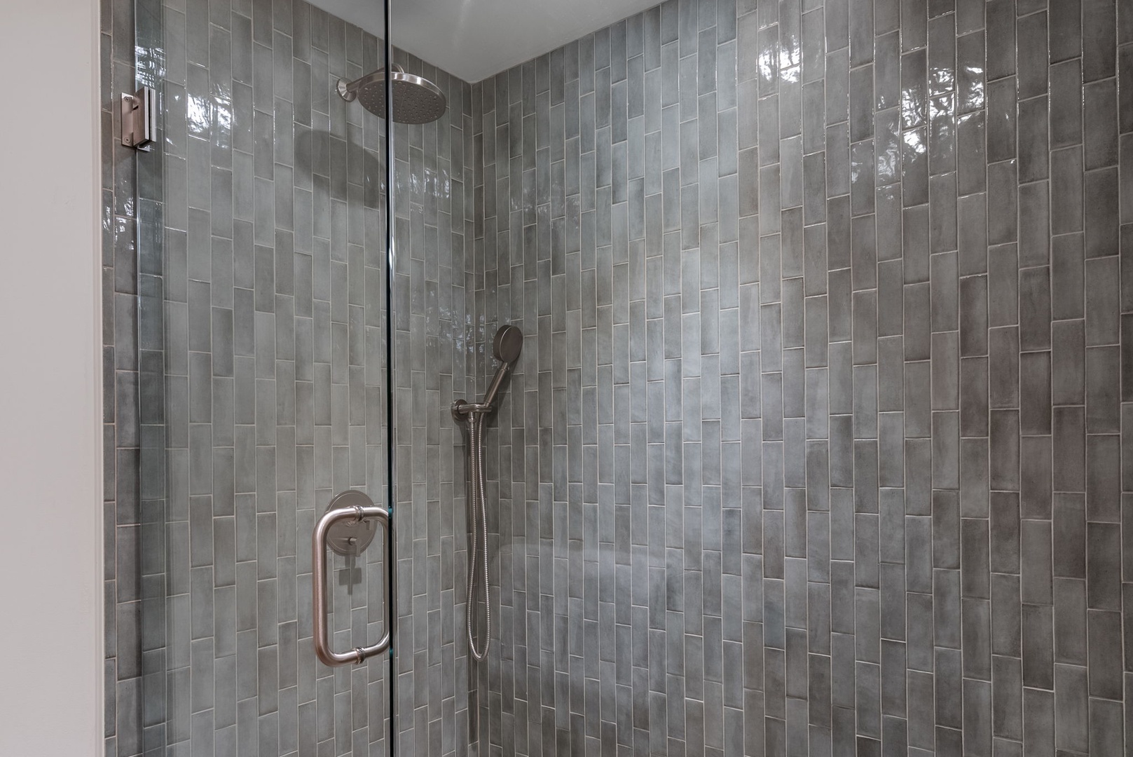 Step into your luxurious glass-enclosed shower with stunning gray mosaic tiles and refreshing rainfall showerhead for the perfect start to your day.