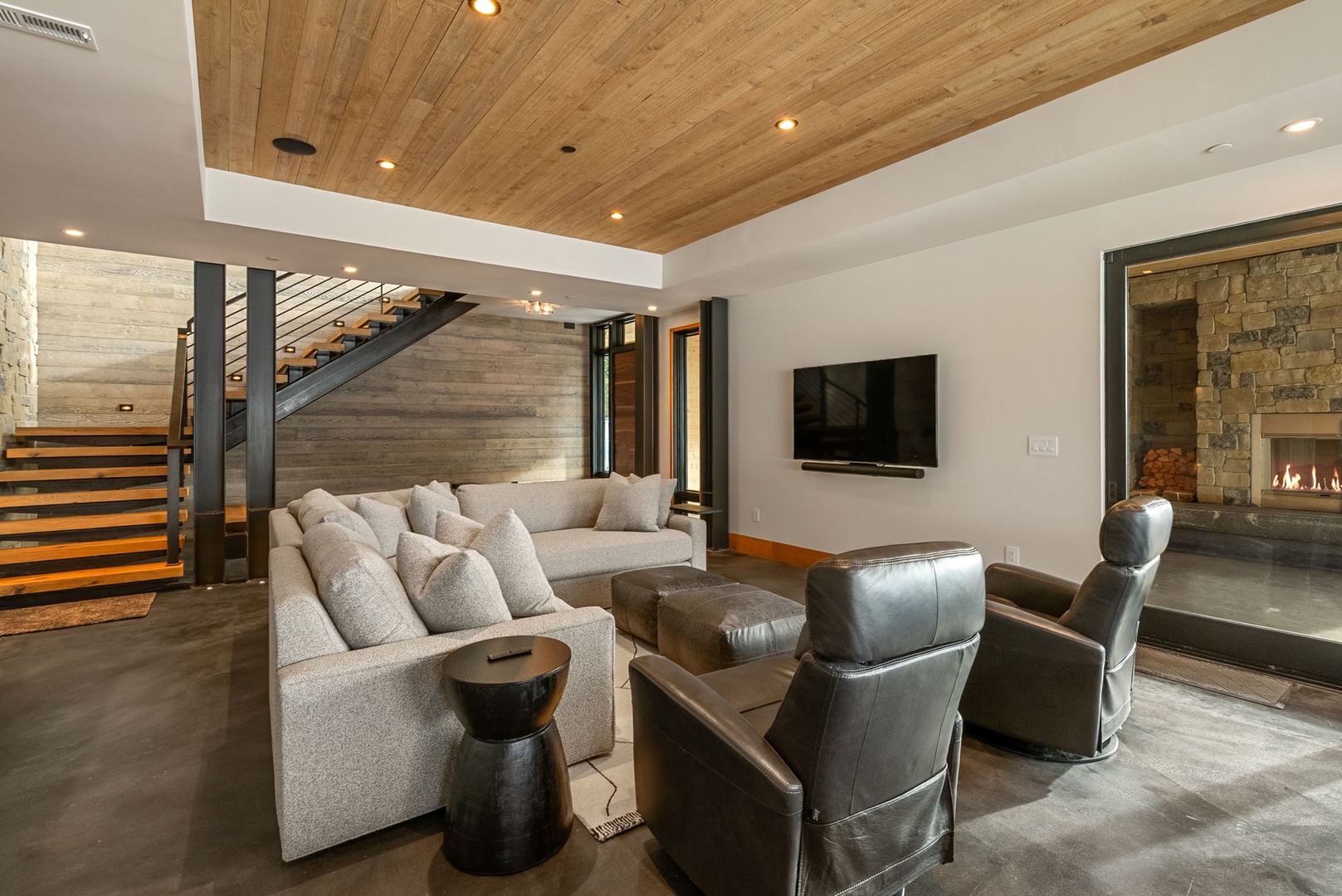 Unwind in your spacious living room featuring plush seating, a cozy fireplace, and warm wood ceiling that creates the perfect atmosphere for relaxation.
