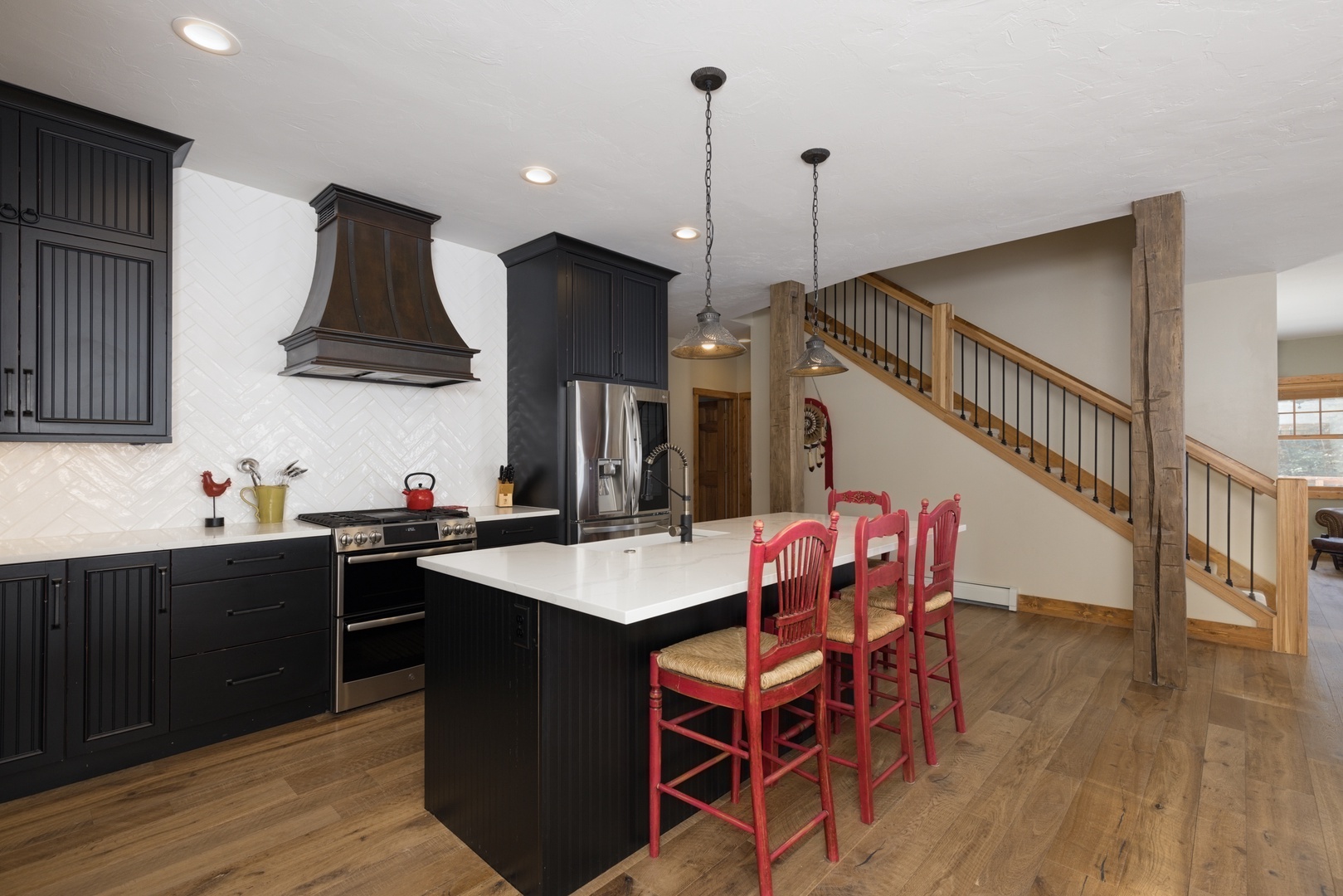 Gather around this stunning kitchen island with charming red bar stools, perfect for morning coffee or evening conversations in your spacious retreat.