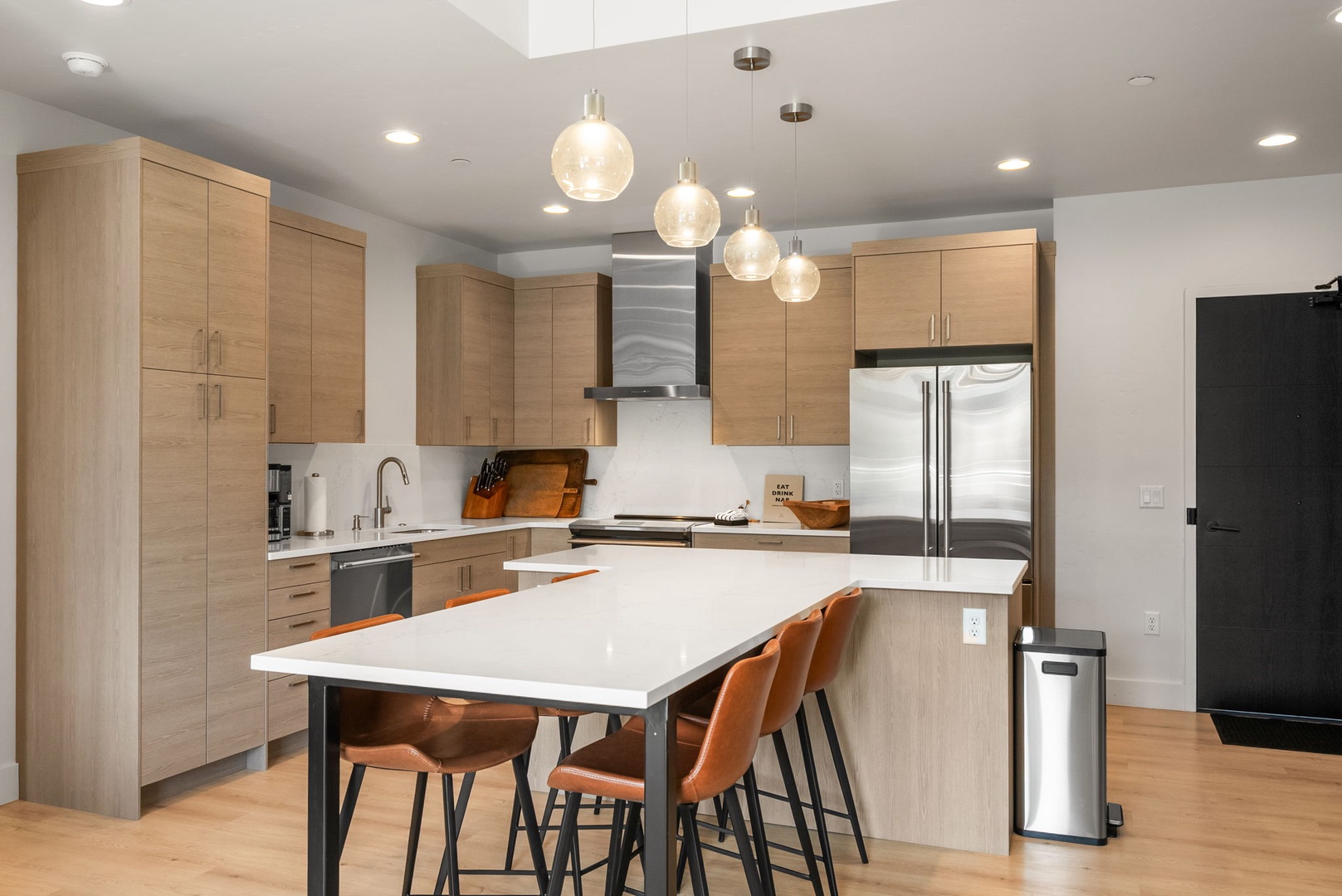 Your stylish kitchen invites you to create and connect, featuring warm wood cabinetry, sleek pendant lighting, and a spacious island with seating—perfect for morning coffee or sharing meals together.