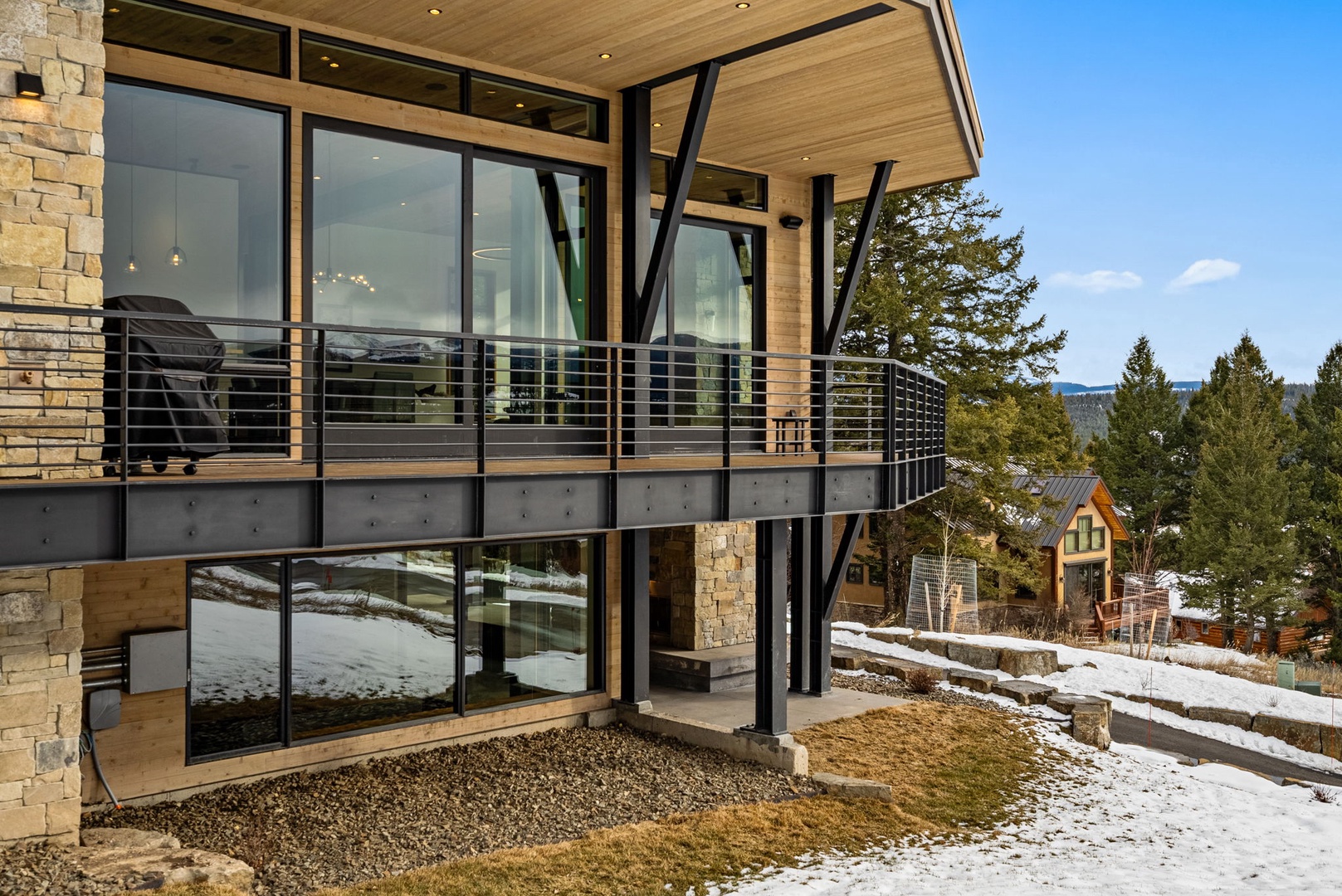 Modern mountain retreat with striking architecture blends stone and glass elements seamlessly with winter landscape.