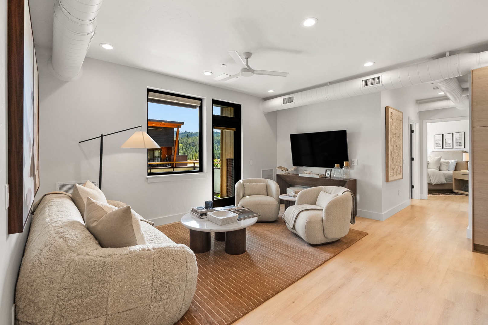 Sink into plush seating in your modern living room, where natural light and warm wood tones create the perfect space for unwinding after exploring the area.