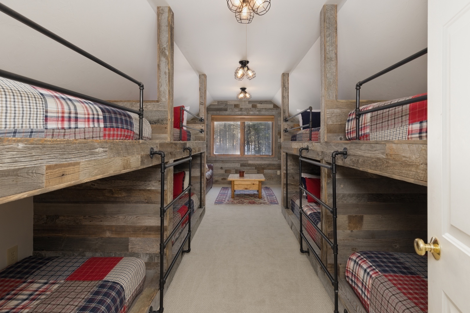 Cozy bunk room with rustic charm sleeps six comfortably. Plaid bedding and warm wood beams create your perfect mountain retreat atmosphere.
