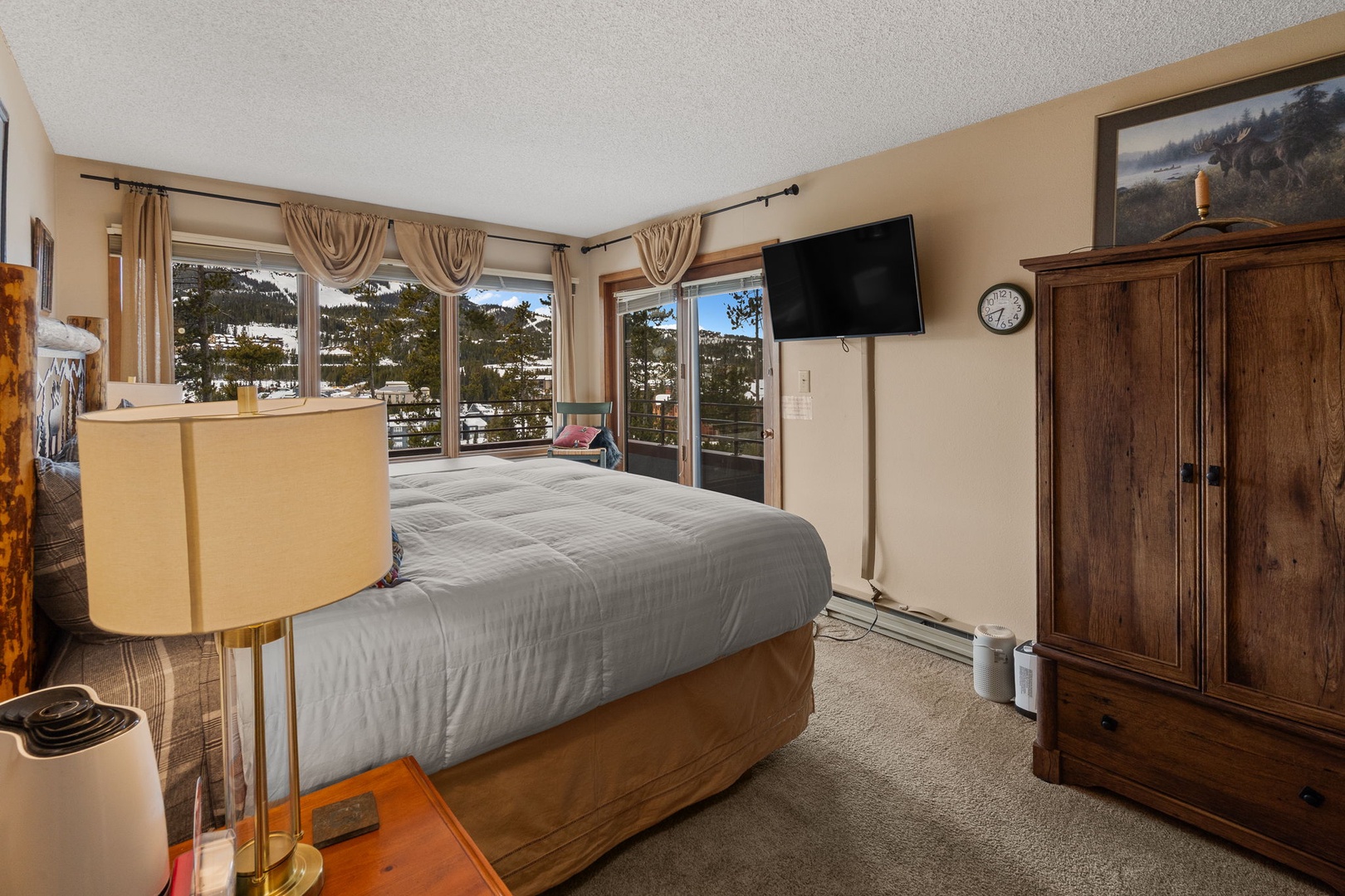 Wake up to stunning mountain views through expansive windows in this cozy bedroom, where warm wood furnishings and modern comfort create your perfect alpine retreat.