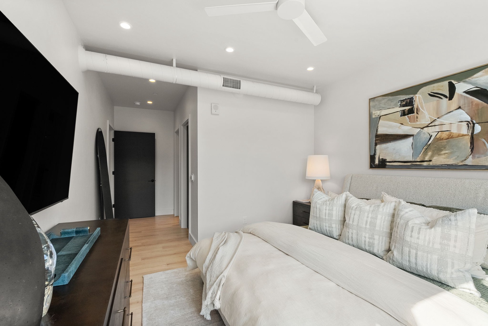 Picture yourself drifting off in this serene bedroom, where crisp white linens meet modern style. The plush bed promises restful nights, while your personal TV and ceiling fan await just steps away.