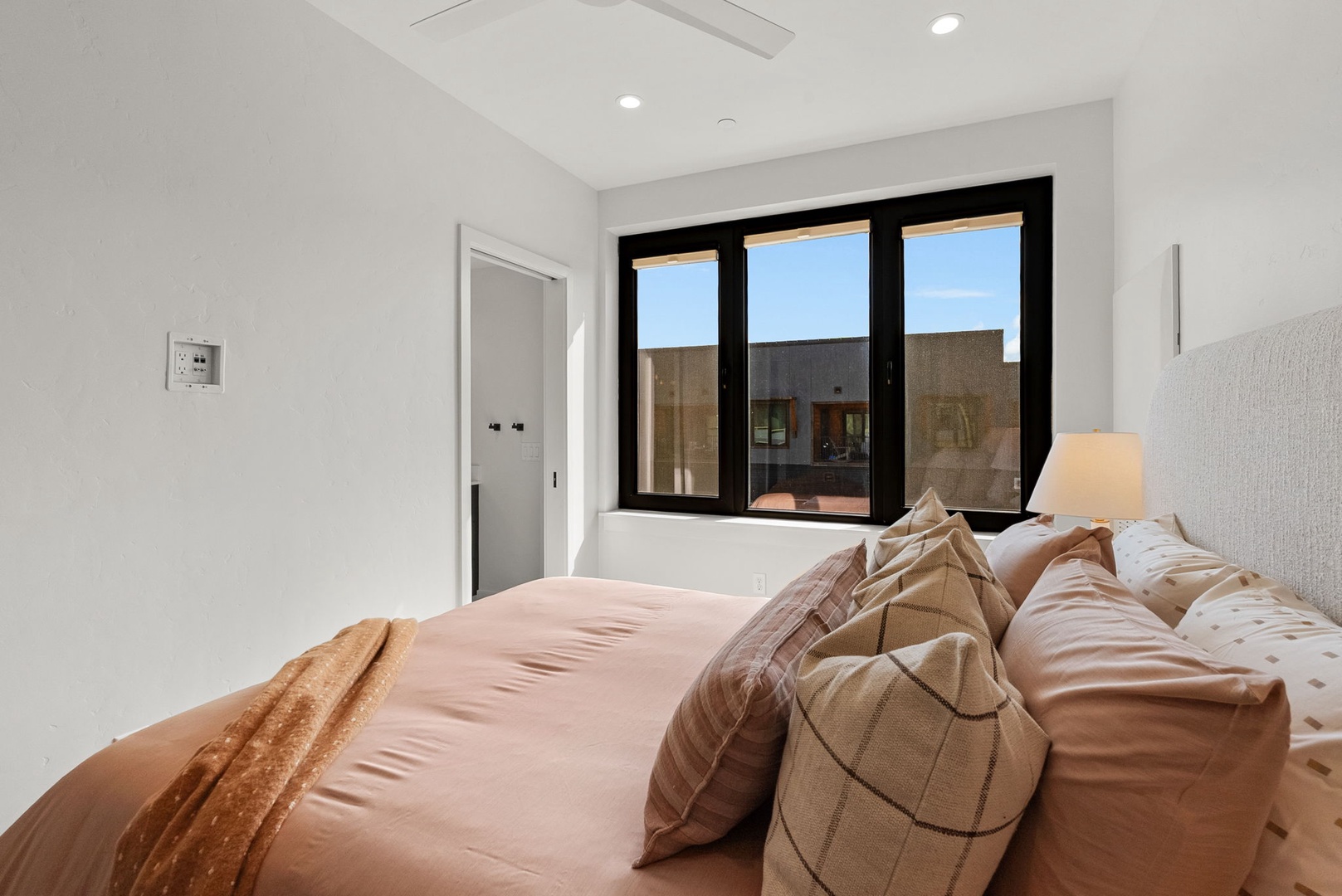 Wake up in your serene retreat with soft natural light streaming through black-framed windows. The crisp white walls and plush bedding create a peaceful sanctuary for your perfect night's rest.