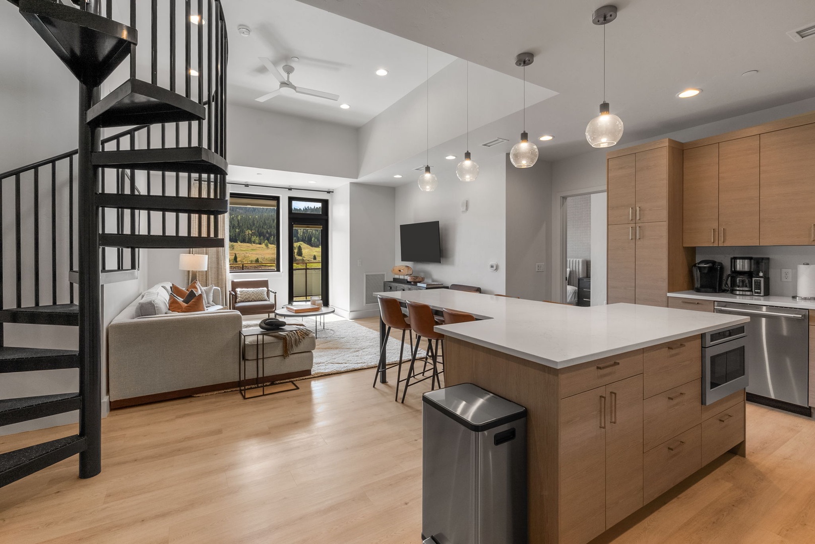 Your open-concept retreat blends mountain living with modern style—sleek kitchen island, warm wood accents, and a spiral staircase leading to your private loft above.