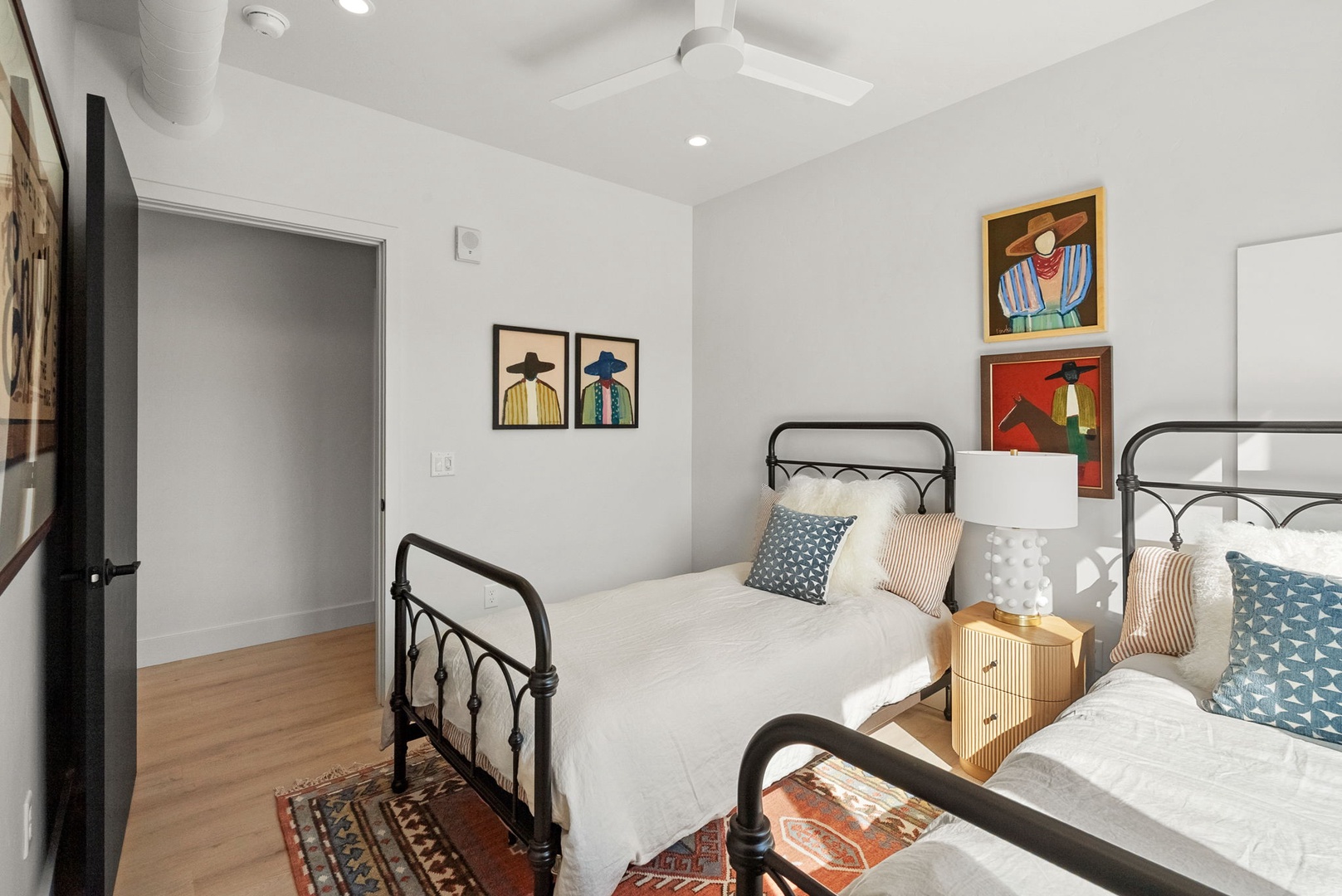 Your bright, airy guest bedroom welcomes with crisp white linens, colorful artwork, and twin beds perfect for family or friends sharing your getaway.