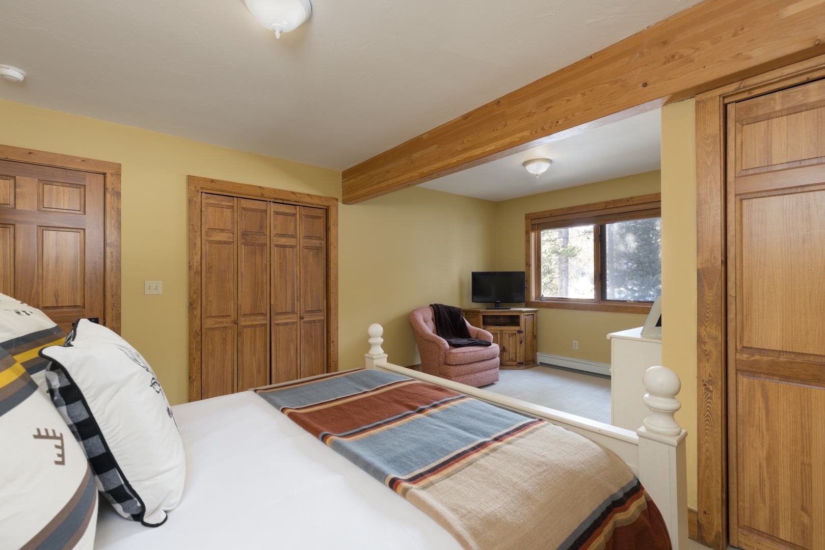 Unwind in your cozy bedroom featuring warm wood beams, built-in storage, and a peaceful reading nook by the window.