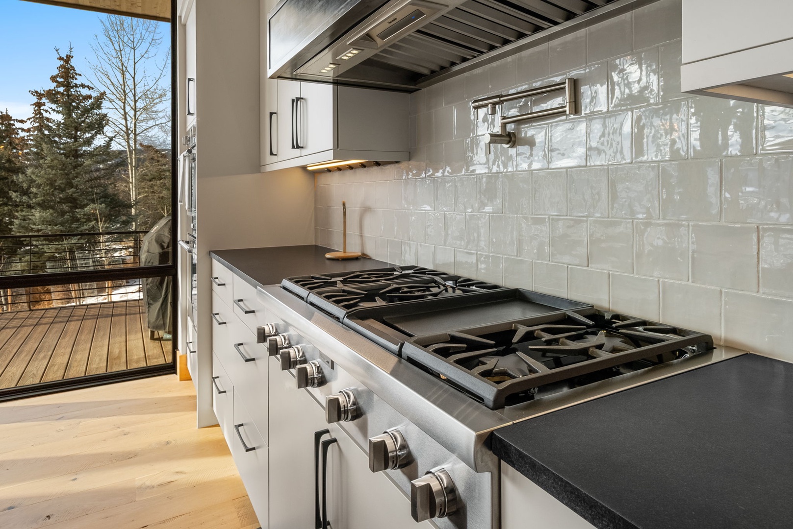 Cook gourmet meals on your professional gas range with sleek countertops and elegant subway tile backsplash in this modern kitchen.