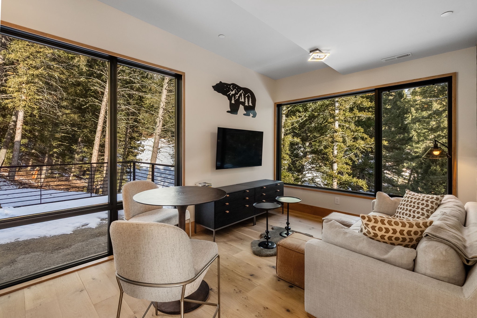 Sink into plush seating while forest views surround you through floor-to-ceiling windows in this cozy living space.