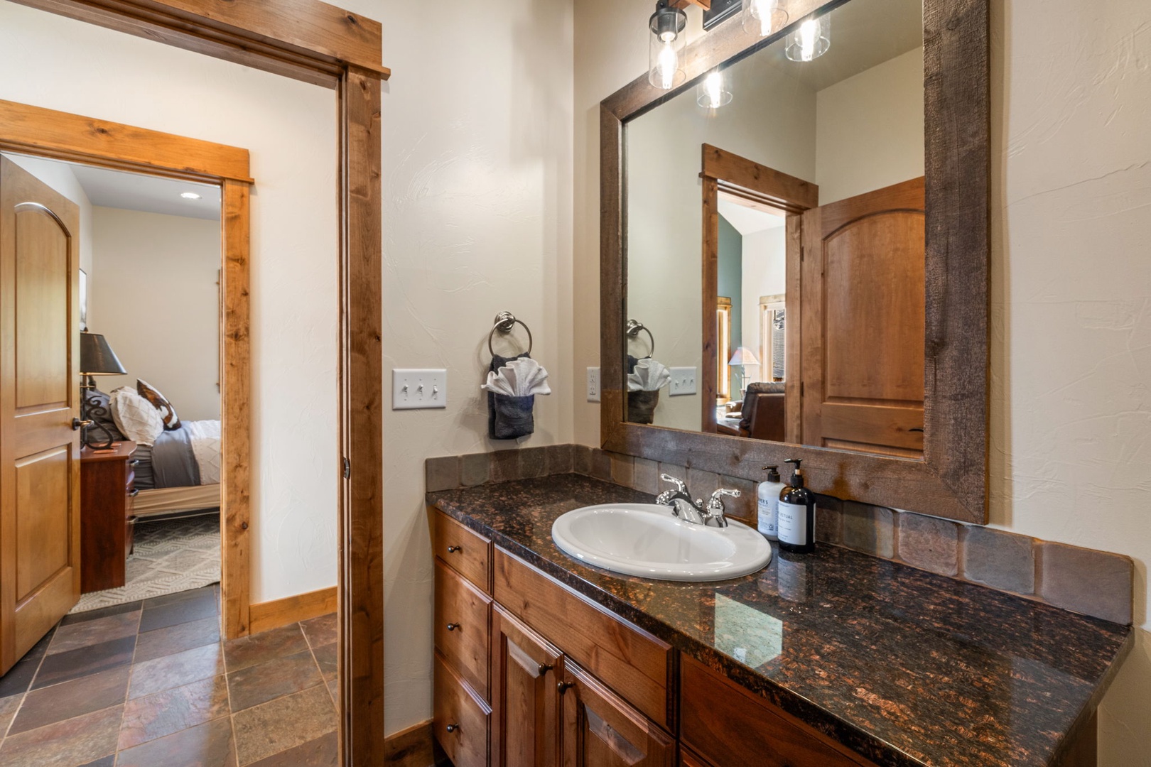 Step into your beautifully appointed bathroom featuring rich wood vanity, granite countertops, and modern lighting that creates the perfect morning routine sanctuary.