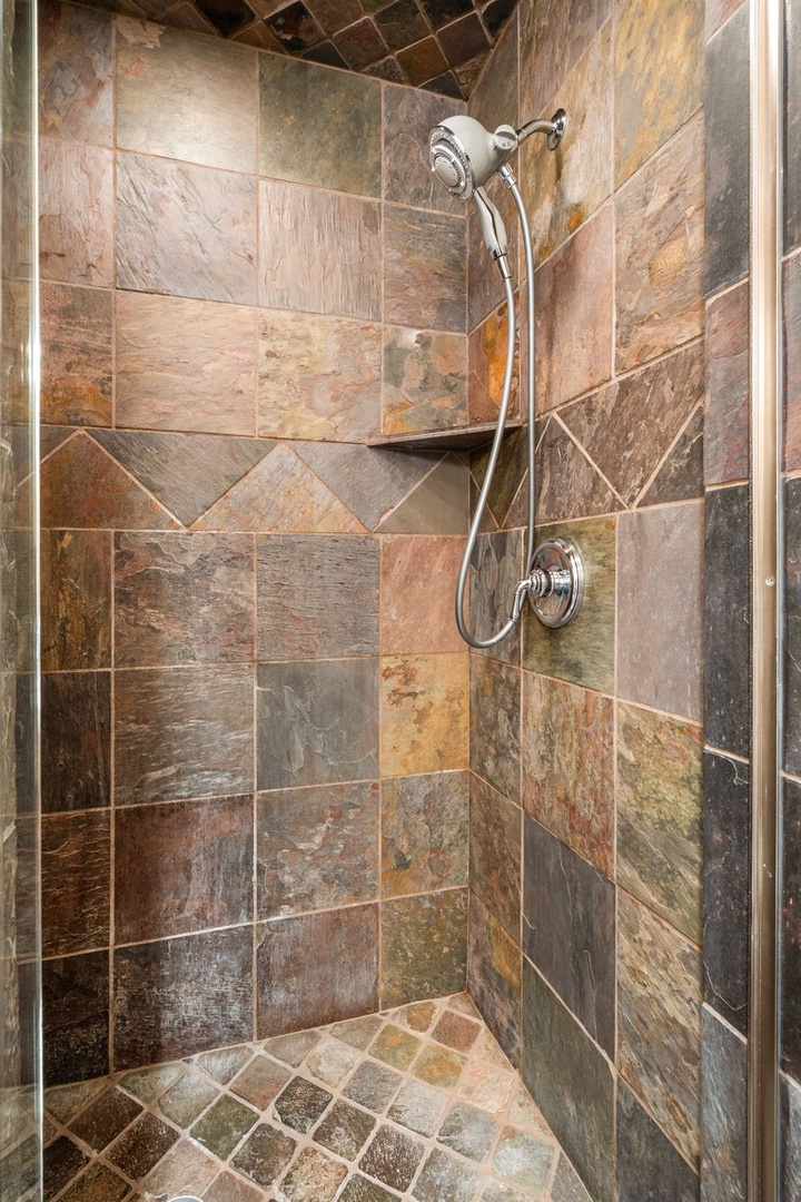 Step into your private stone-tiled shower, where natural slate creates a spa-like retreat for your daily refresh.