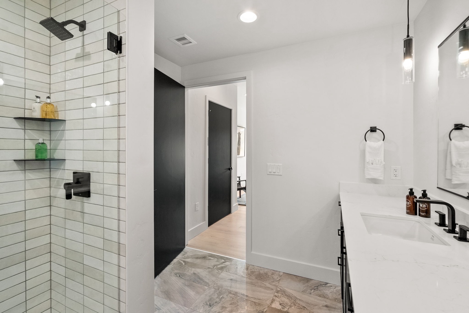 Sleek white subway tile meets modern black fixtures in your spa-inspired ensuite. The spacious walk-in shower and crisp countertop create a clean, minimalist retreat for your morning routine.