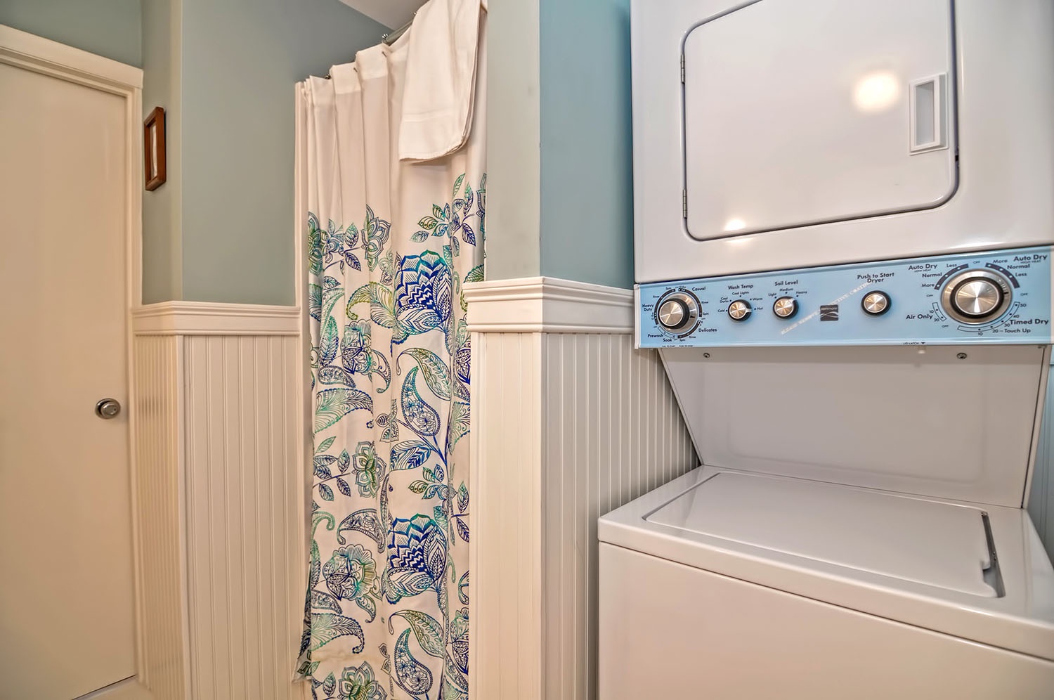 Shower and a stacked washer and dryer.