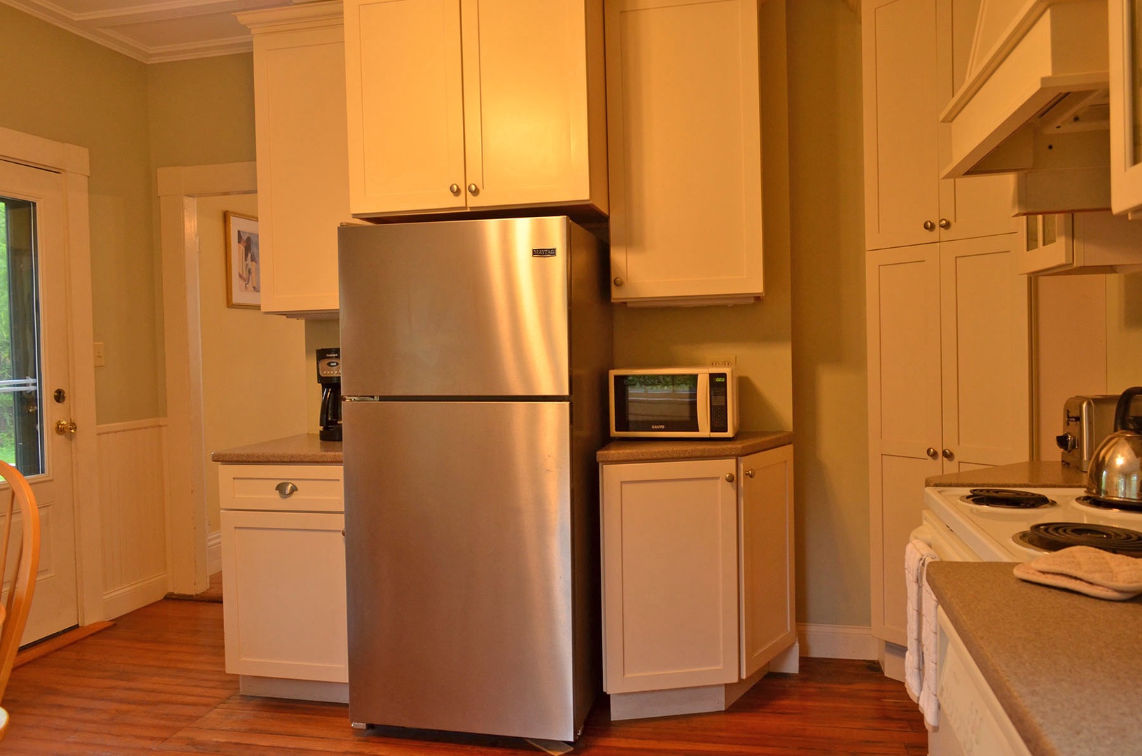 Kitchen has stainless steel refrigerator, microwave, and coffee pot.