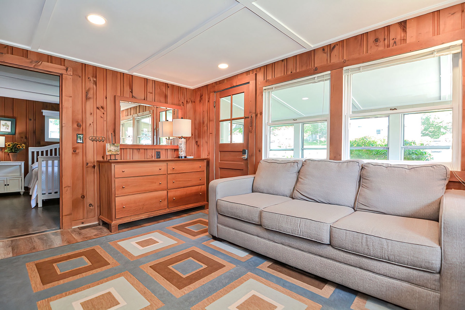The wood-paneled living with the front door to the sunroom.